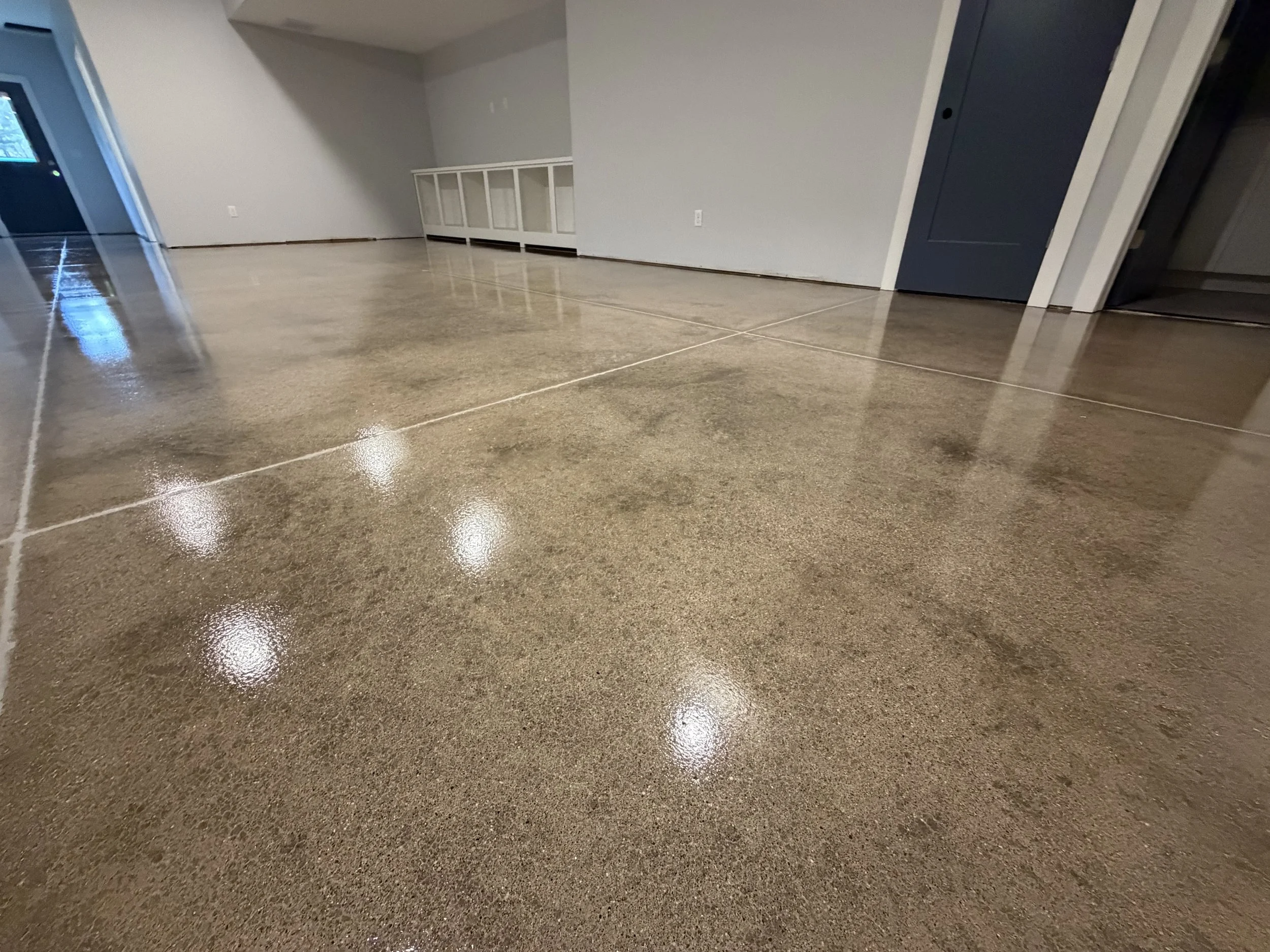 Polished concrete floor in empty room, reflecting ceiling lights.