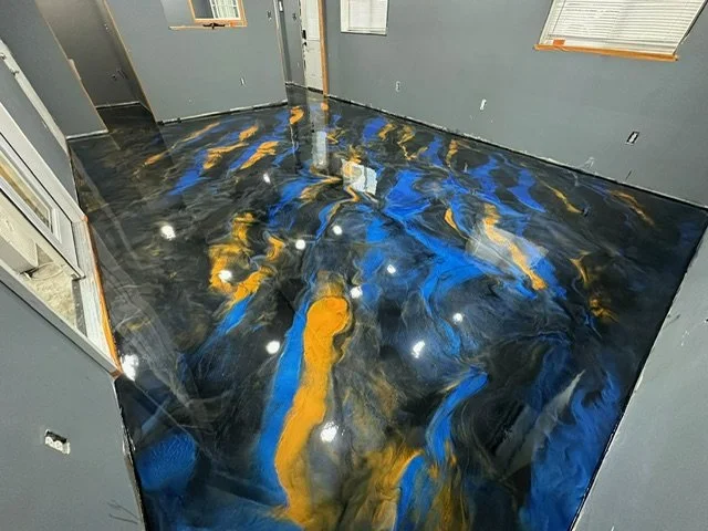 Interior room with a highly reflective epoxy resin floor in black, blue, and yellow swirl patterns.