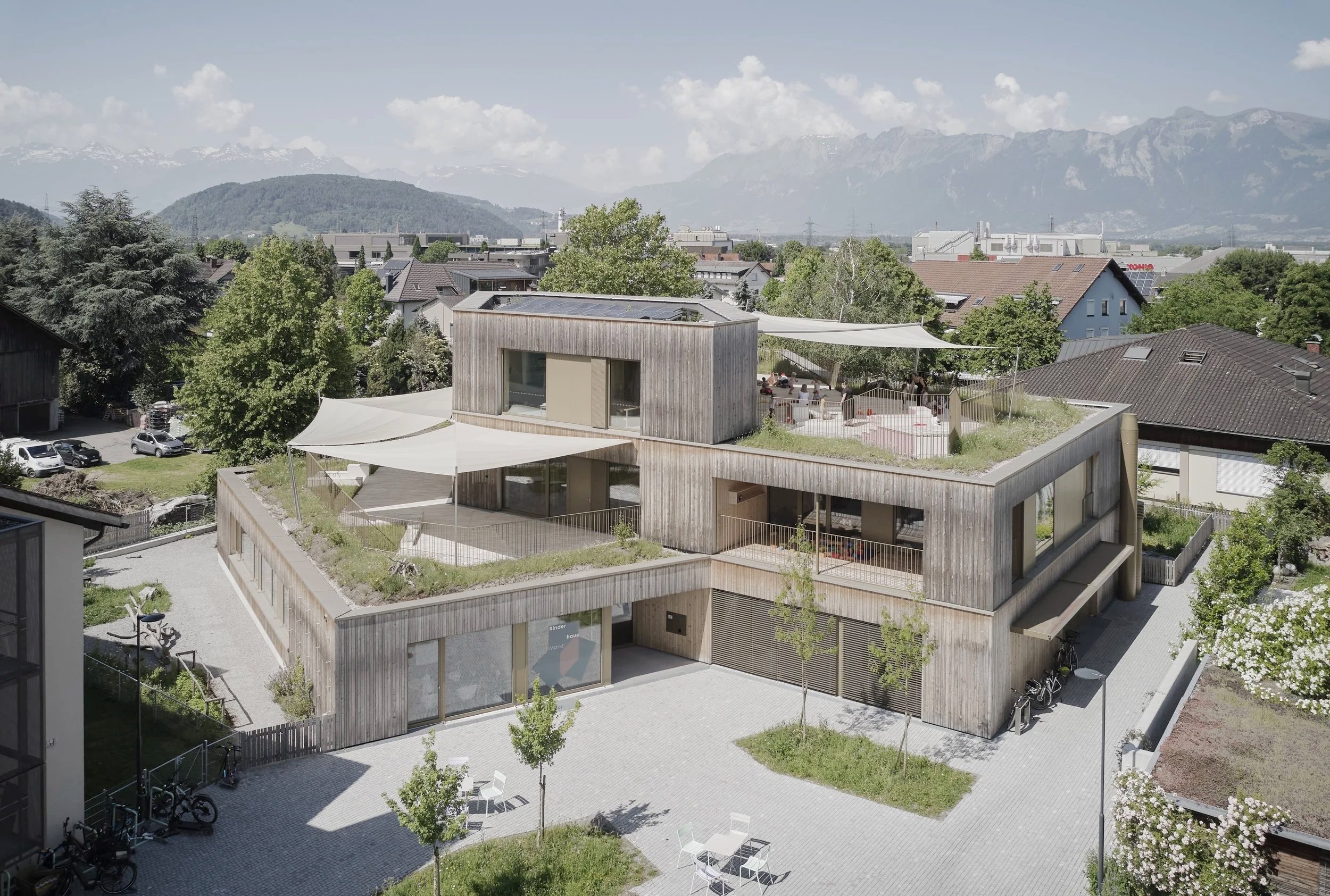 Kinderhaus Rankweil Markt | Eingangsbereich mit Vorplatz | Gebäude mit verschatteten Dachterrassen | Foto Marc Lins