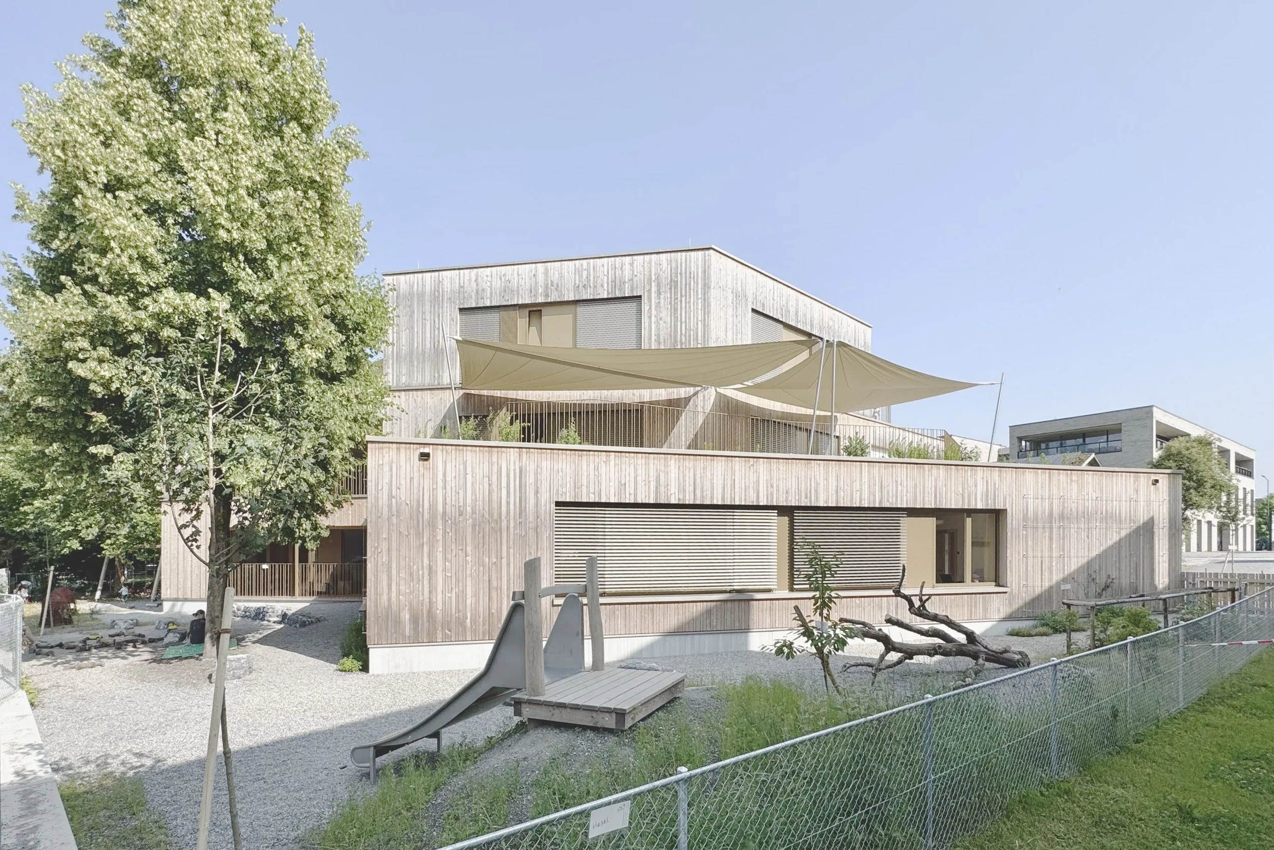 Kinderhaus Rankweil Markt | Baukörper mit verschatteten Aussenspielbereichen auf 3 Ebenen