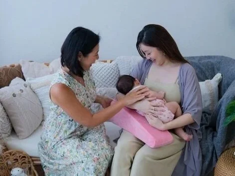 Mayvina Wee from Manna Milk Lactation guiding a mother on comfortable breastfeeding positions using a nursing pillow.