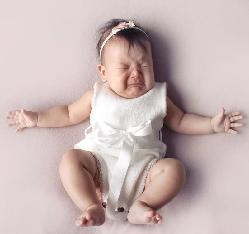 A crying baby representing the common frustrations and pain mothers face during early breastfeeding challenges.