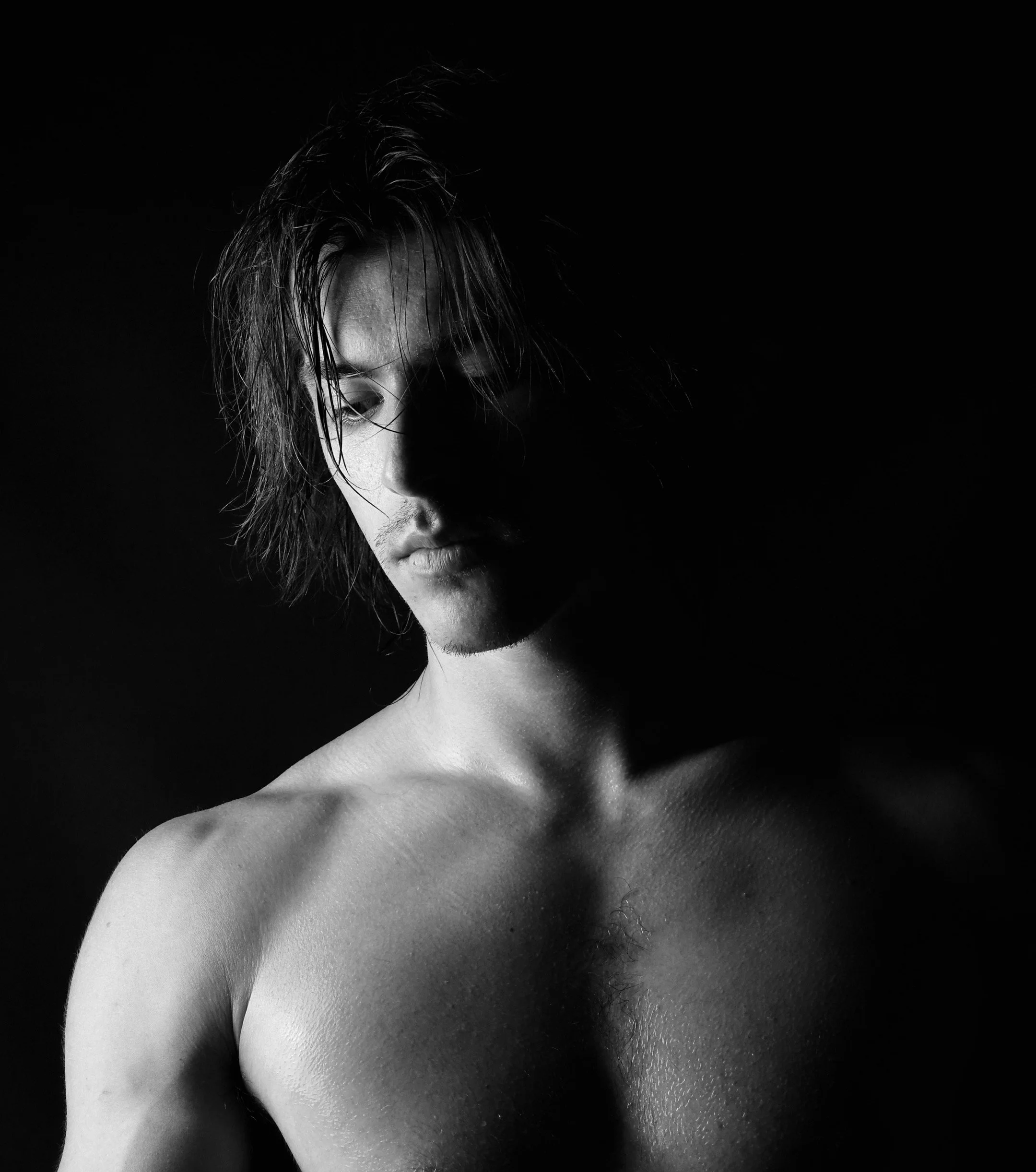 Black and white photo of Francesco Pividori: a shirtless young man with wet hair, looking down, with shadowed face and visible shoulder.