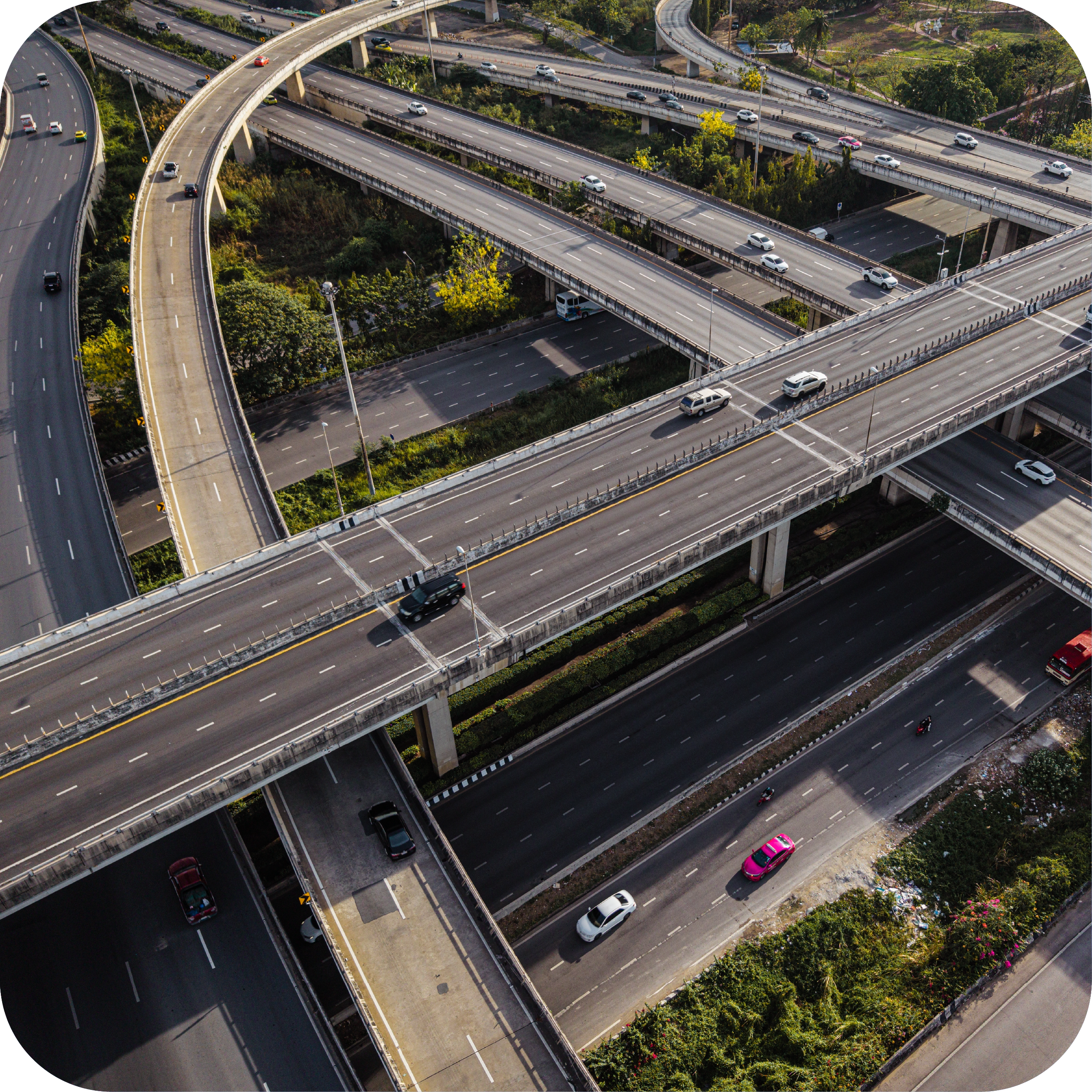 Multiple overpasses and roads with cars, surrounded by green trees and vegetation in an urban area.