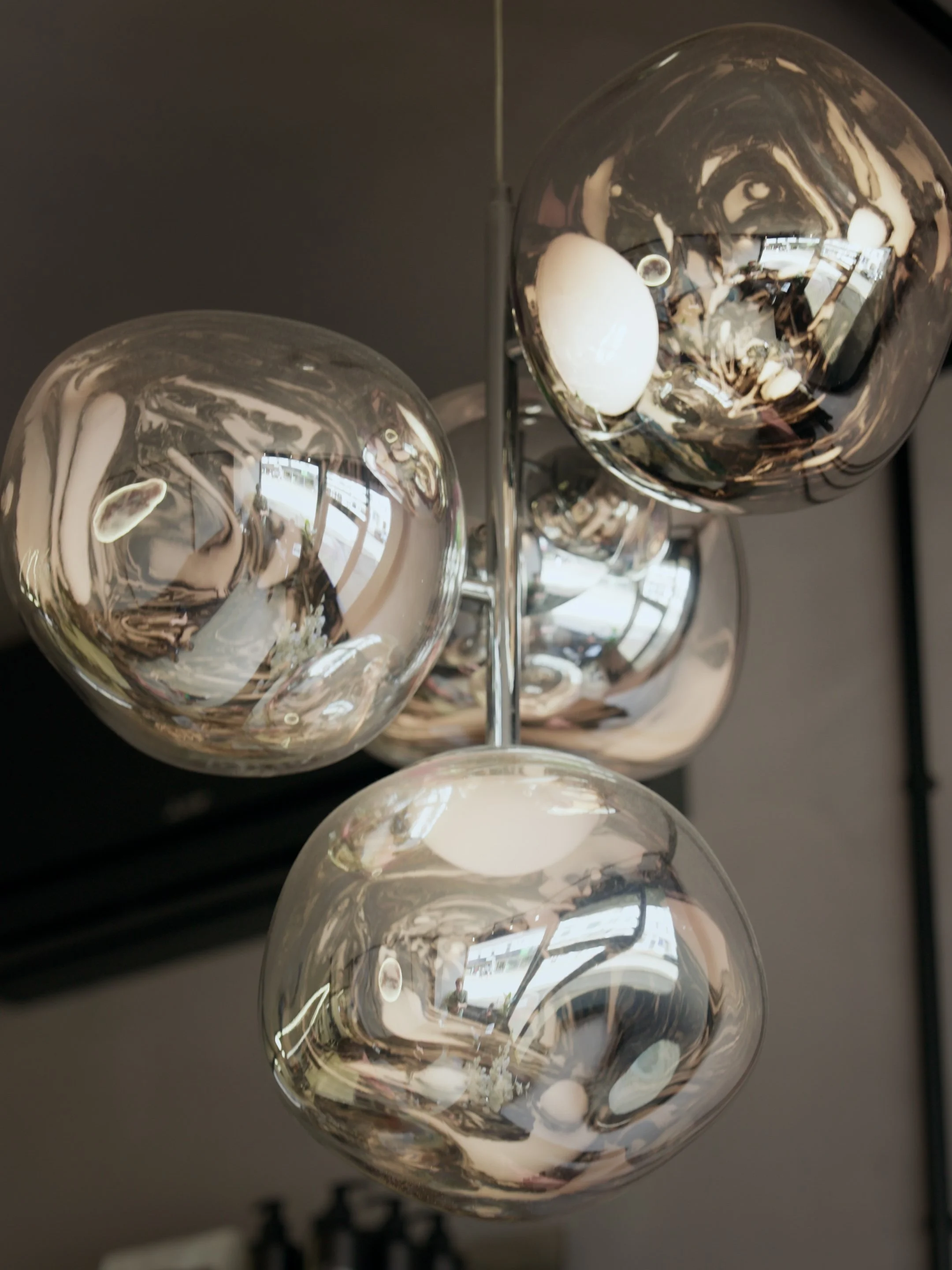Close-up view of a modern chandelier with several transparent glass globes hanging from a metallic frame, reflecting their surroundings.