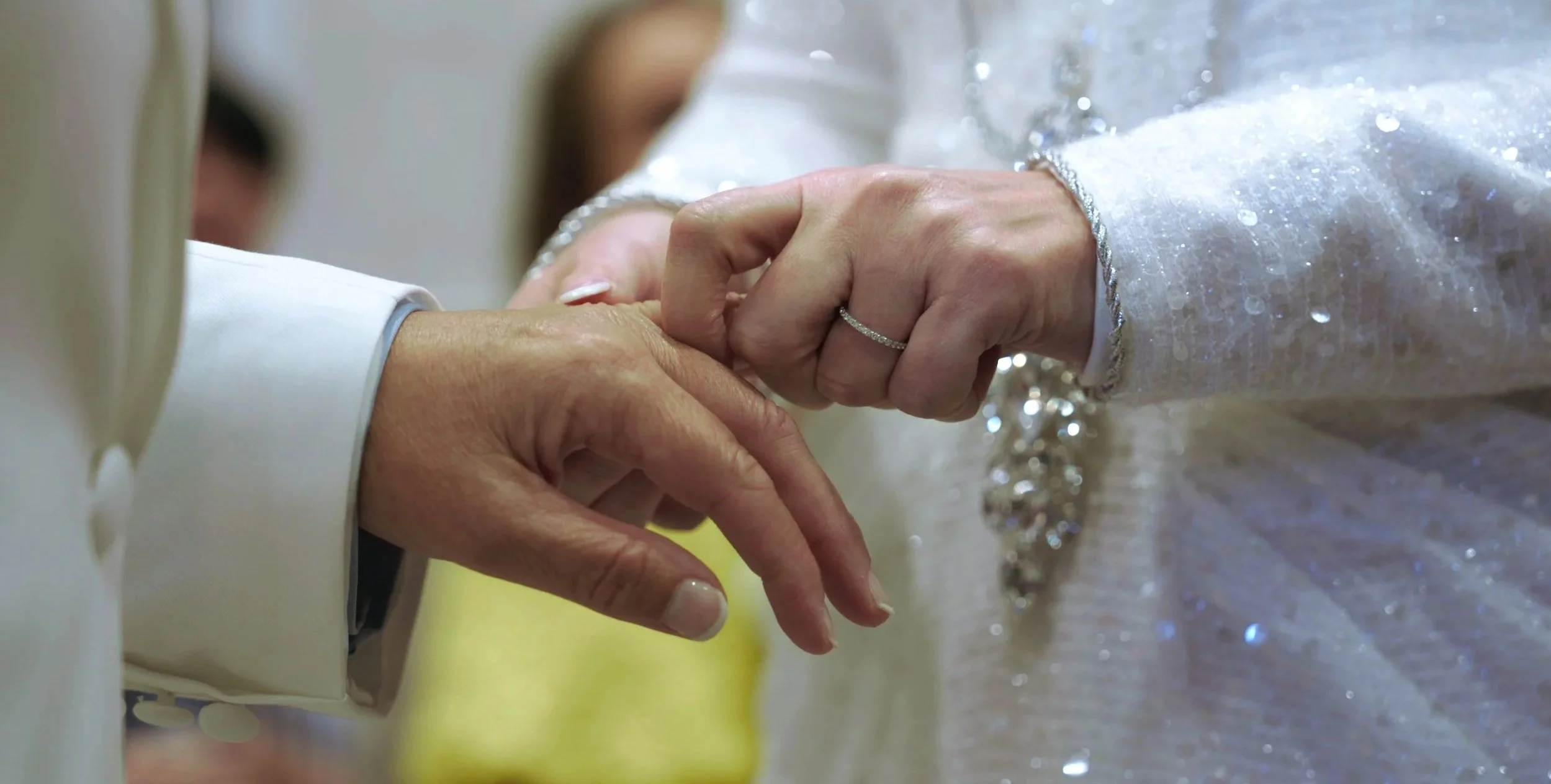 Close-up of a bride and groom exchanging wedding rings during their ceremony.
