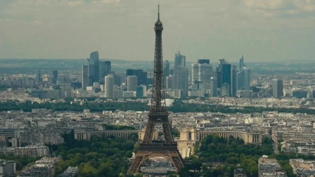 Aerial view of the Eiffel Tower with the Paris city skyline in the background.