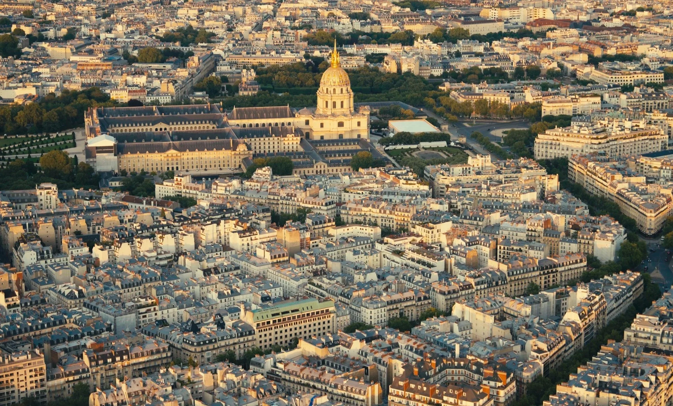 Aerial view of Paris, France, featuring the Église du Dôme des Invalides with its golden dome, surrounded by city buildings and streets.