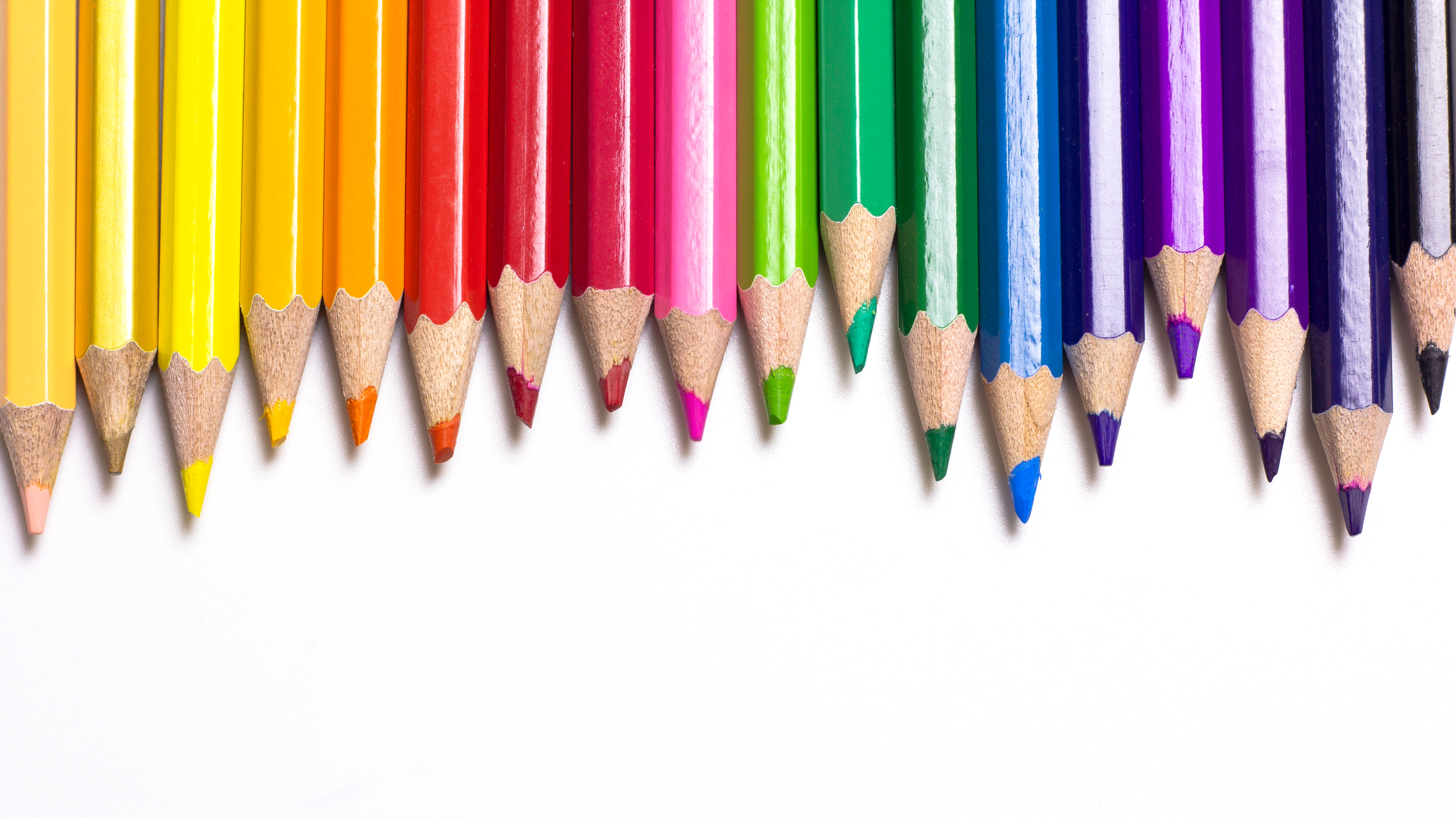 Sharpened colored pencils arranged by rainbow colors.