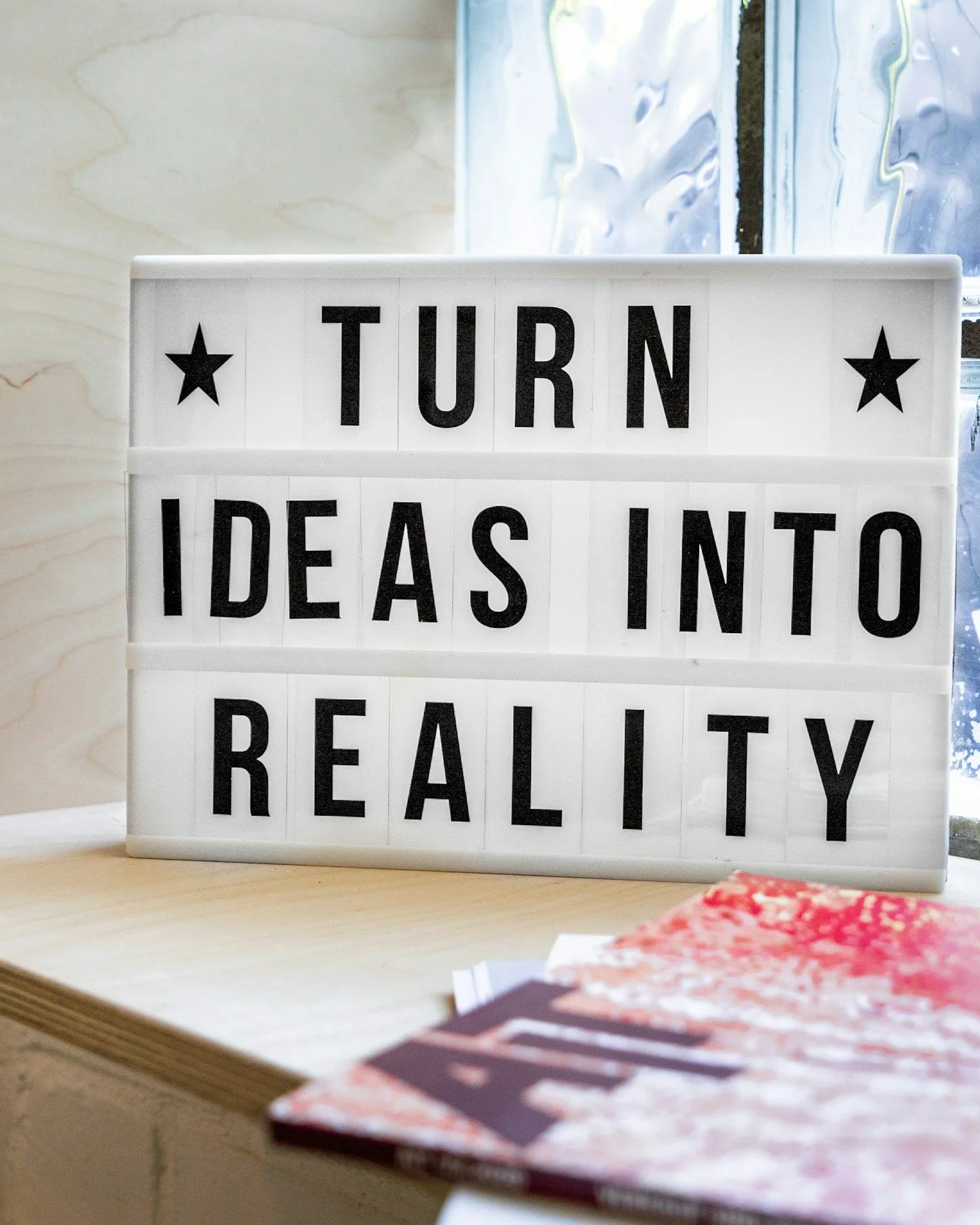 Whiteboard with black letters in front of window- reads Turn Ideas Into Reality.