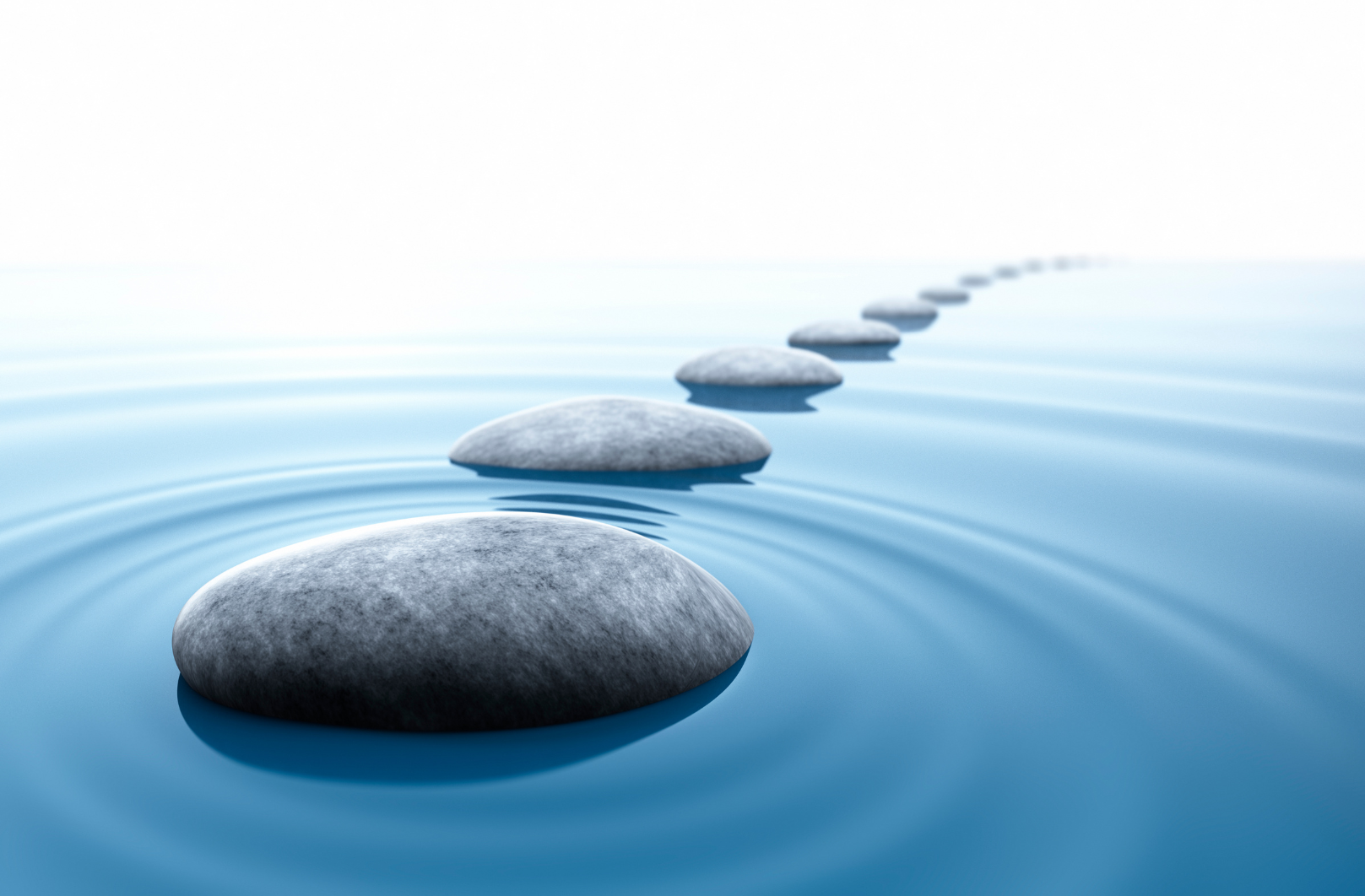 Gray stepping stones across a blue lake.