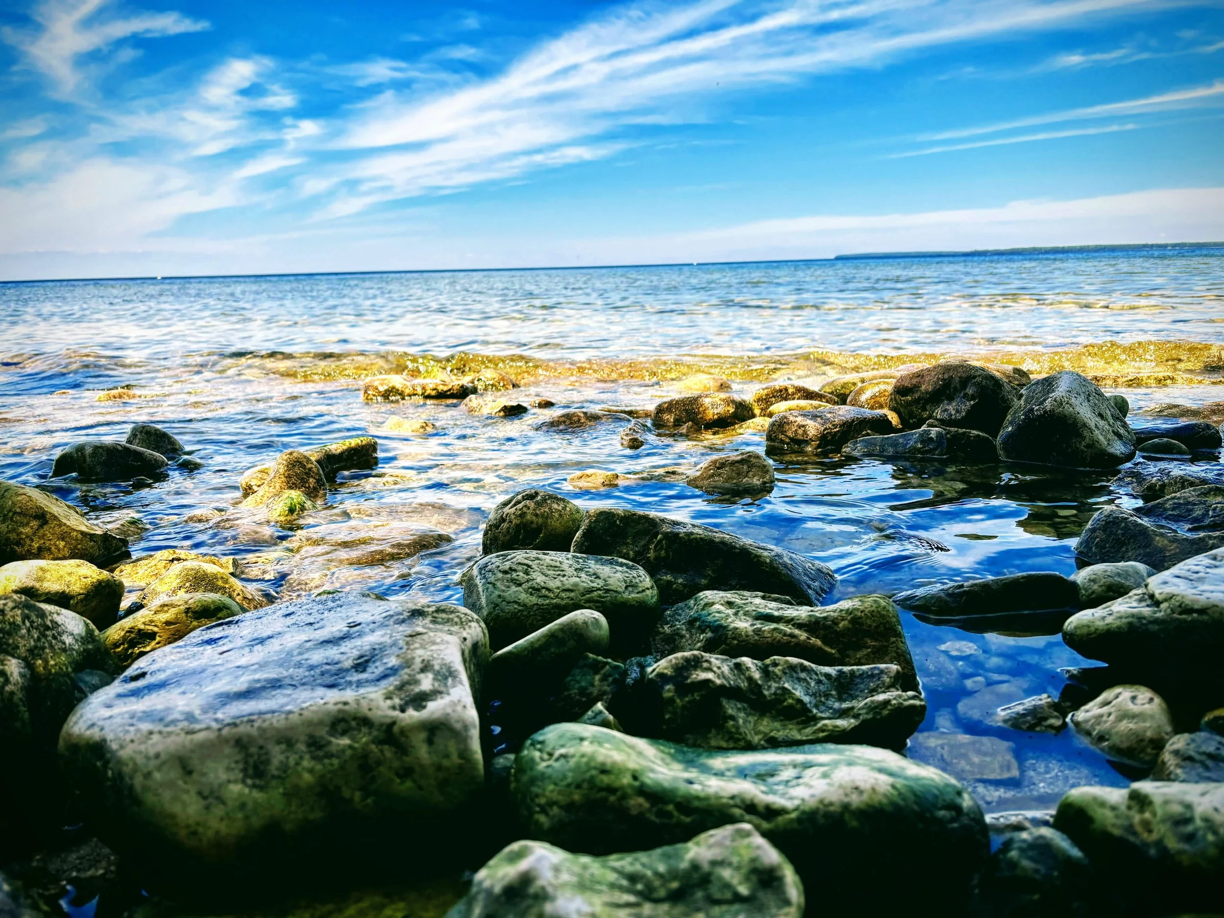 Rocky shore along the Lake Superior shoreline on a sunny day taken by Kalin Schoephoerster.