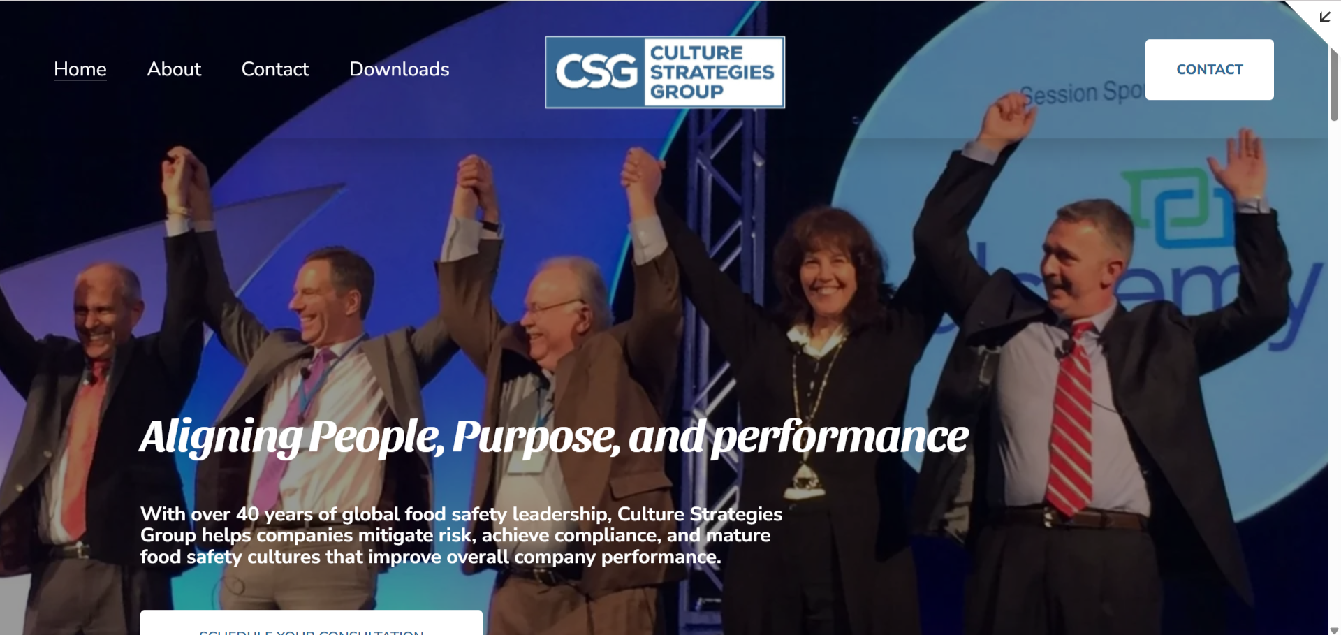 Group of six professionals on stage, holding hands with their arms raised in celebration.