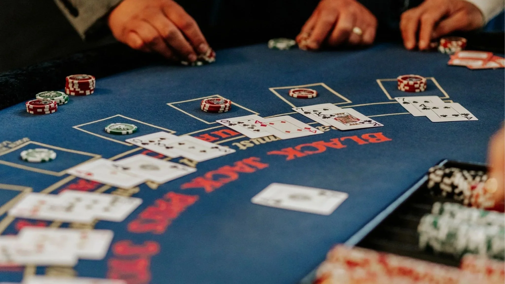 Players betting with poker chips and playing cards on a blue casino table