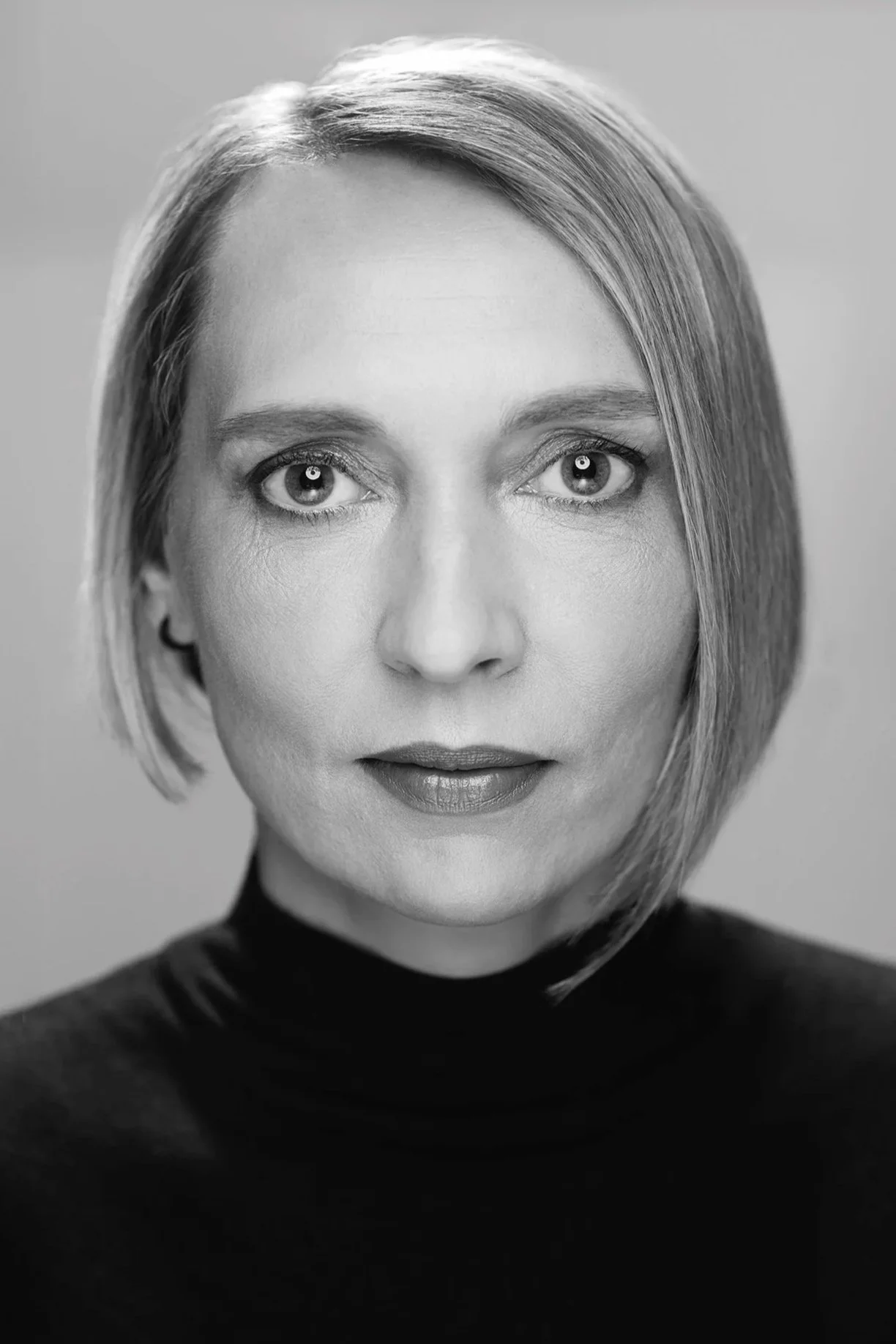 Black and white portrait of a woman with short, straight hair, wearing a turtleneck, looking directly at the camera.