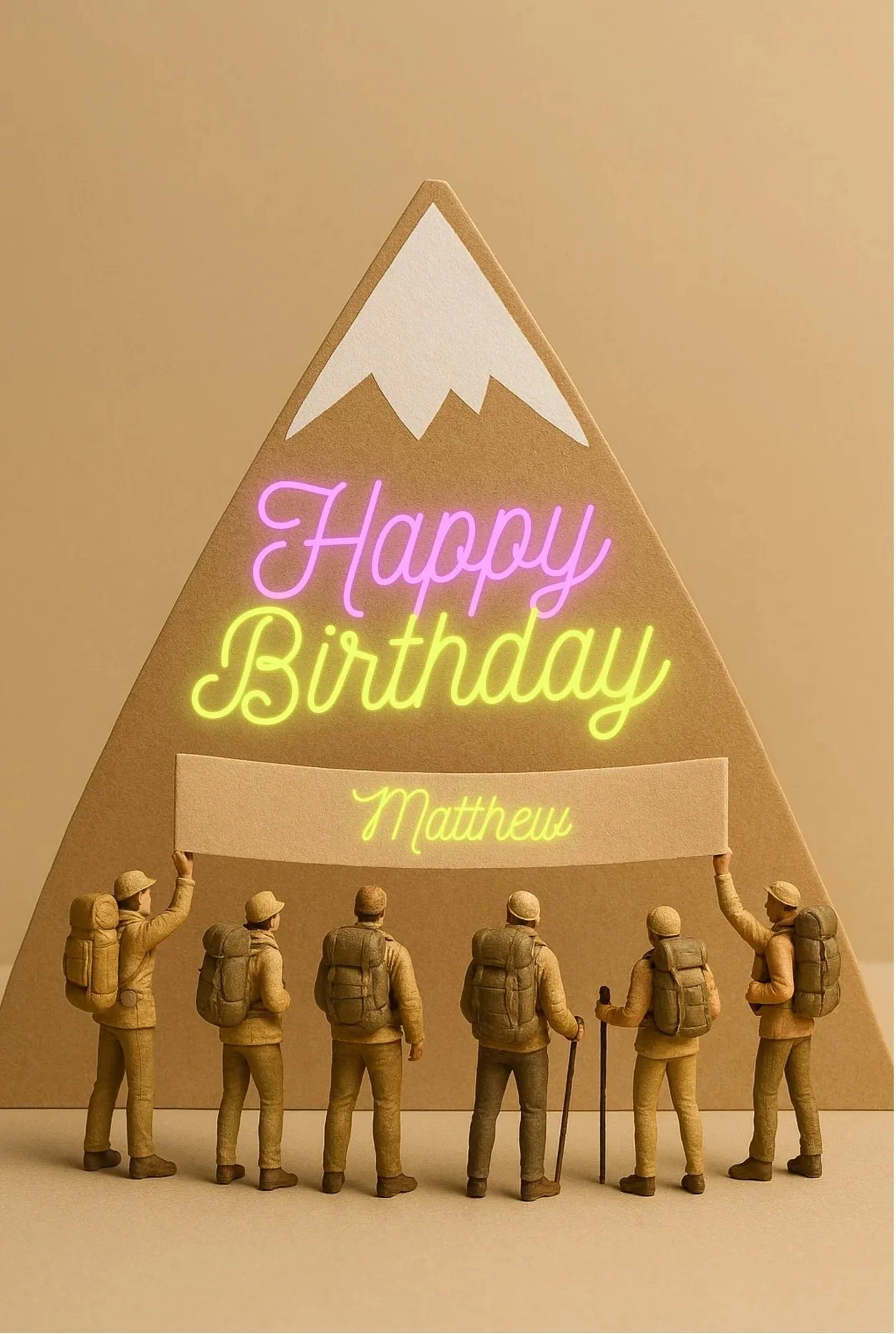 Miniature hikers standing in front of a mountain-shaped birthday sign with a neon message that reads 'Happy Birthday Matthew'.