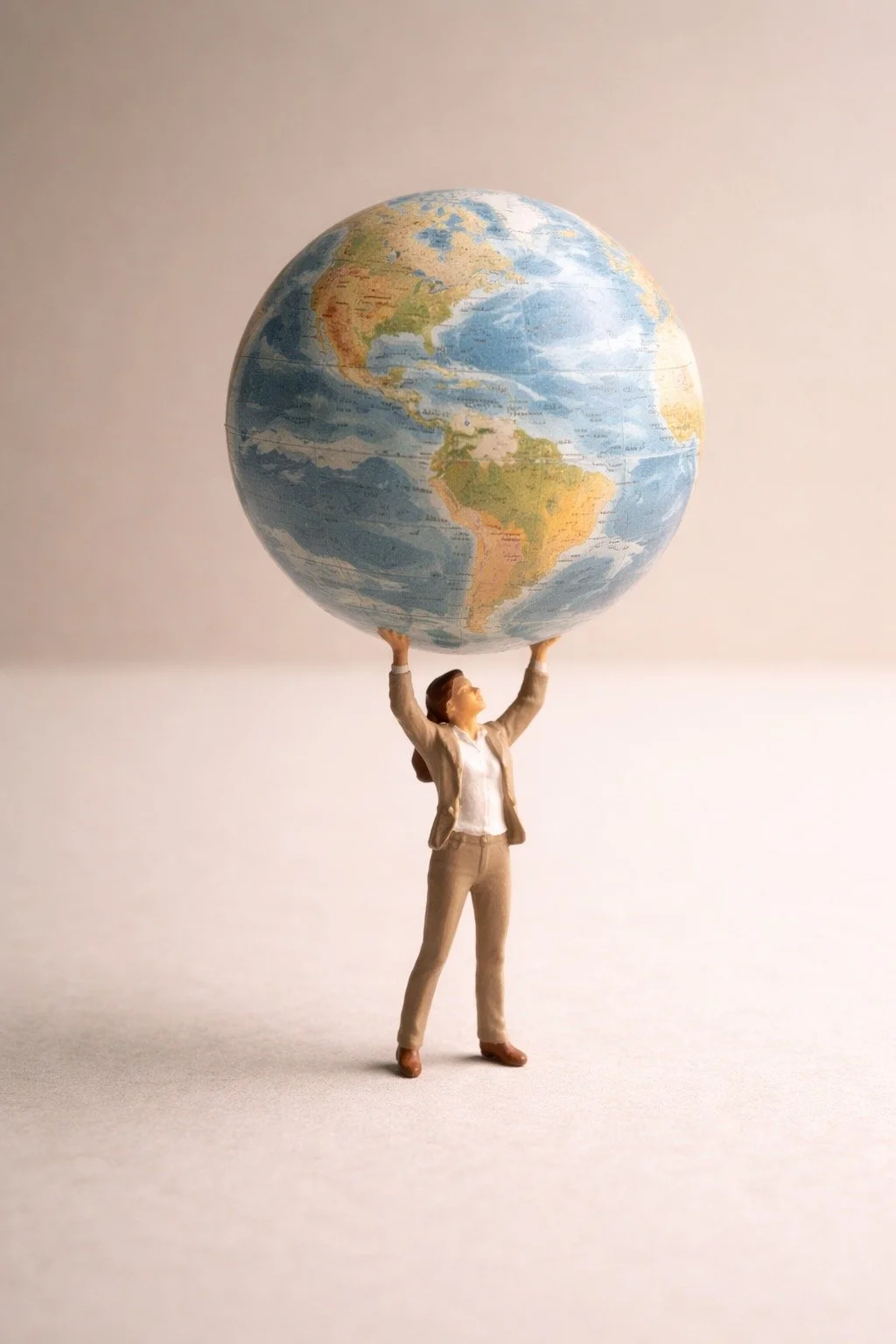 A miniature woman figurine holding a large inflatable globe at shoulder height.