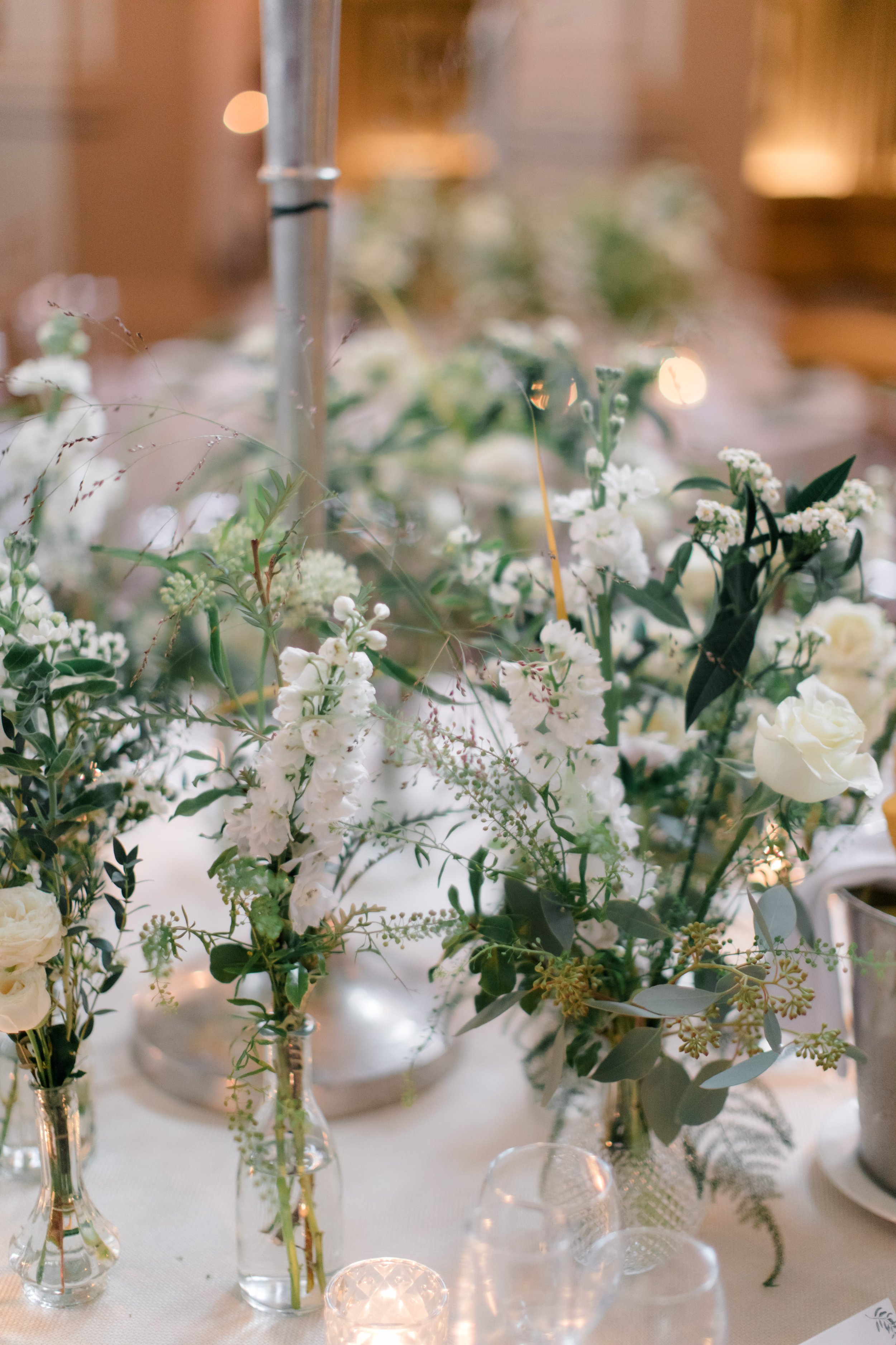 Elegant floral centerpieces with white flowers and greenery on a wedding table.