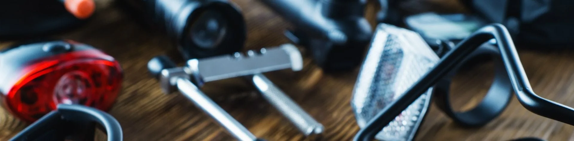 Fietsonderdelen op een houten tafel, inclusief lamp, reflecterend apparaat en gereedschap.