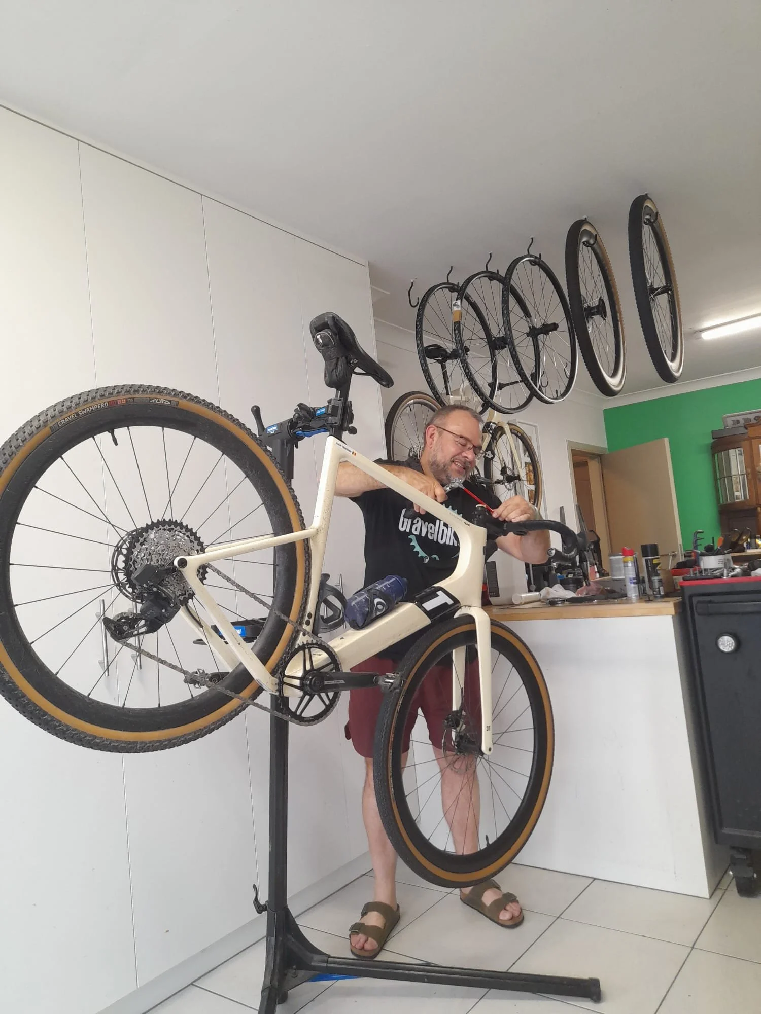 Man repareert een witte mountainbike die op een bike repair stand staat in een keuken.