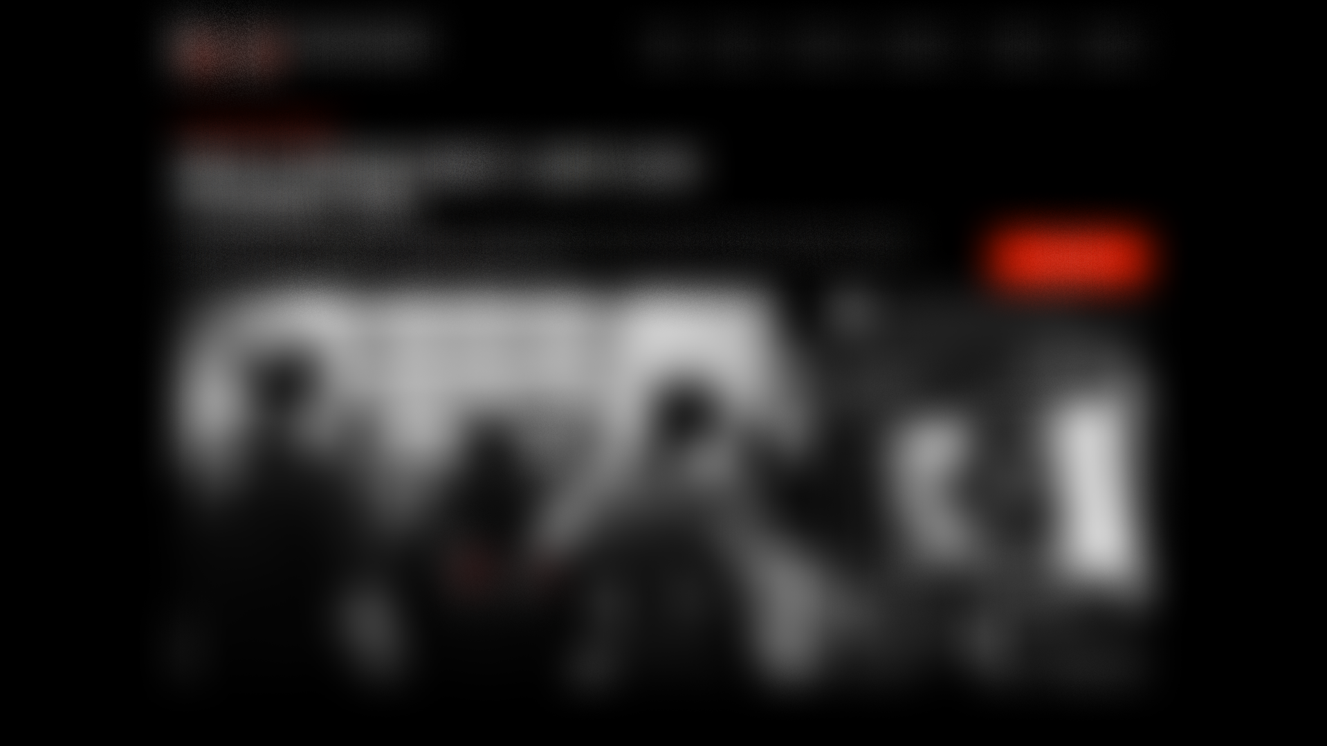 A dark background with blurred images of a television screen, some red text, and objects that appear to be electronic devices or gaming equipment.