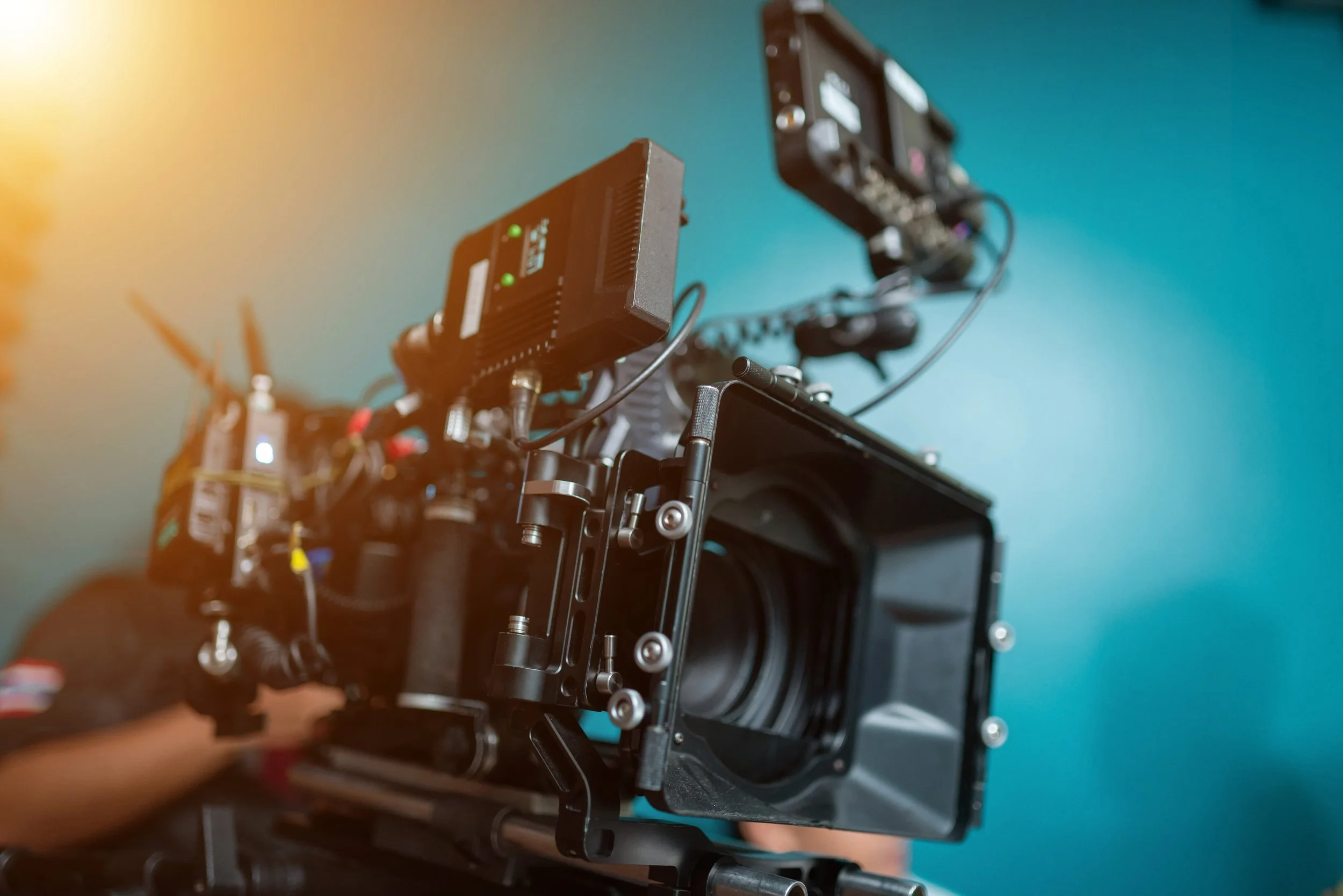 Close-up of a professional camera setup with electronic equipment mounted on a rig, against a blue background.