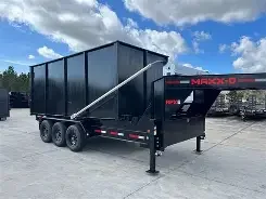 Black dump trailer with a tall, enclosed bed and dual axles parked on a paved lot under a partly cloudy sky.