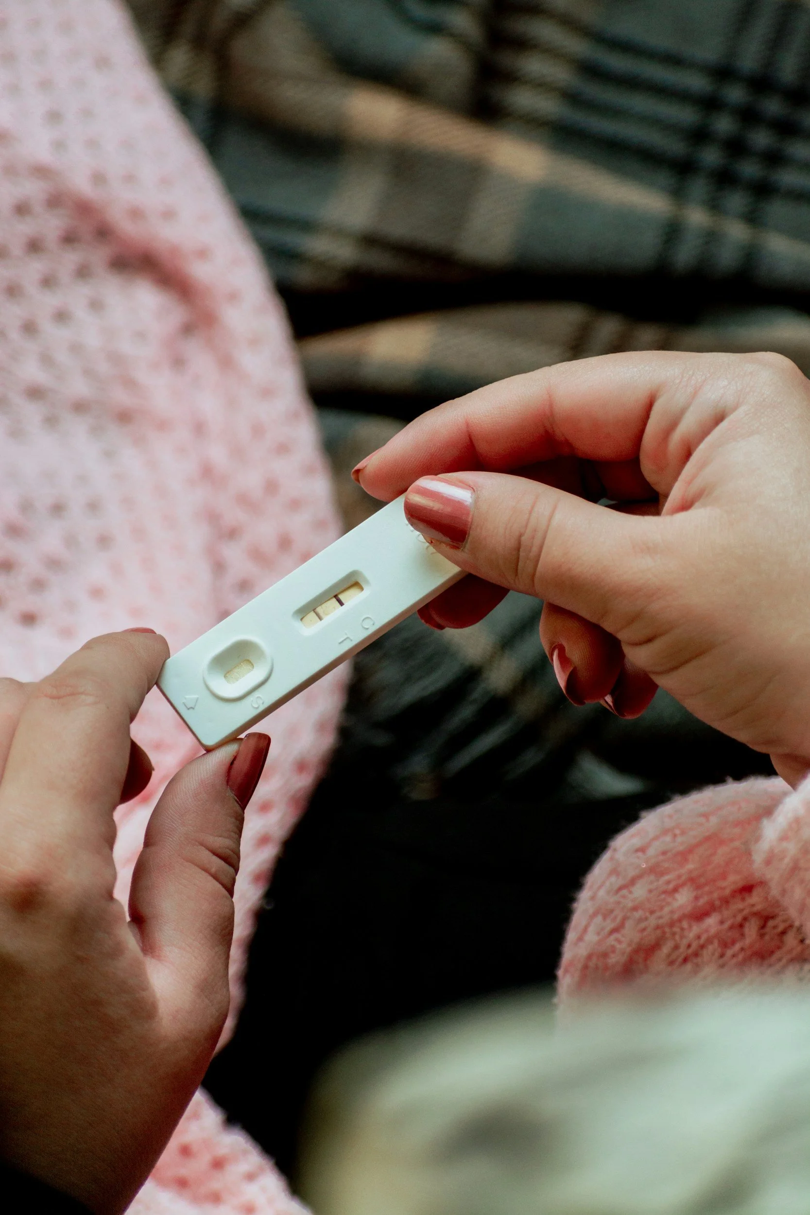 A person holding a positive pregnancy test with two visible lines, indicating a positive result.