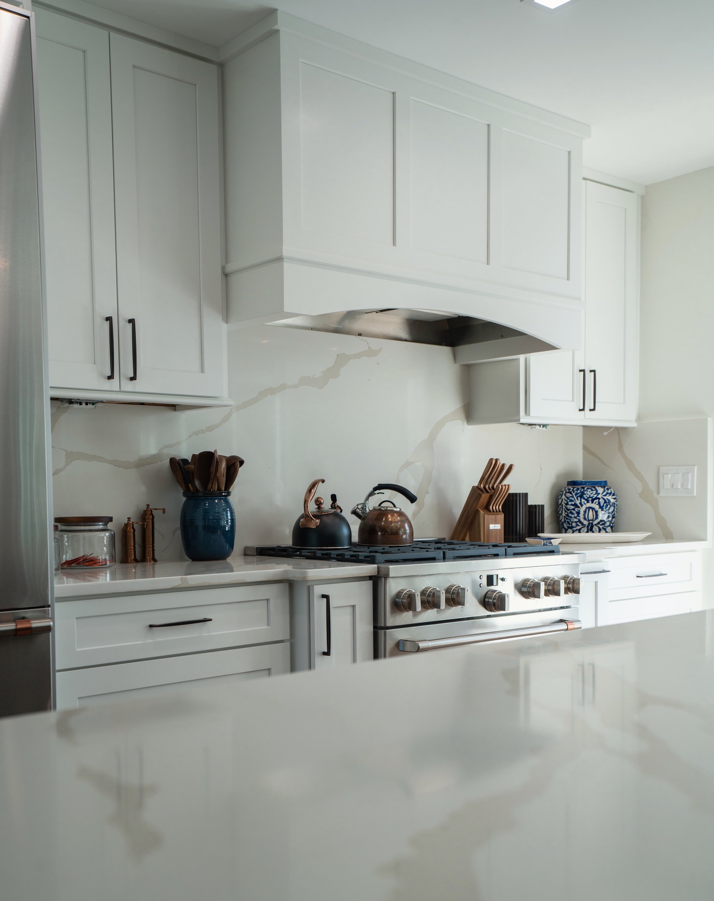 Modern kitchen with white cabinets, a stainless steel stove, and decorative kitchenware on the countertop.