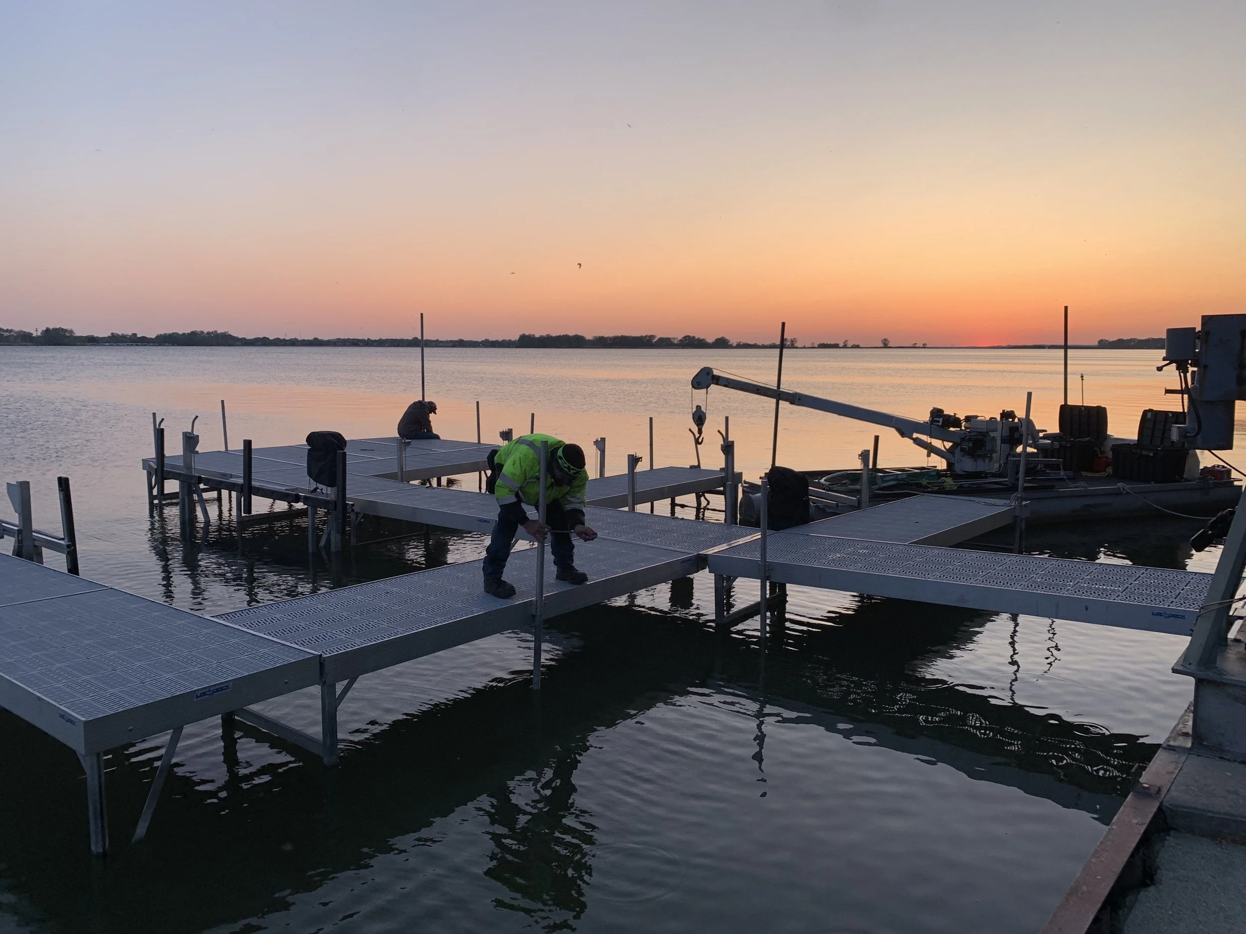 Pipe Creek Enterprises crew installing a new dock with a beautiful sunset over Lake Erie