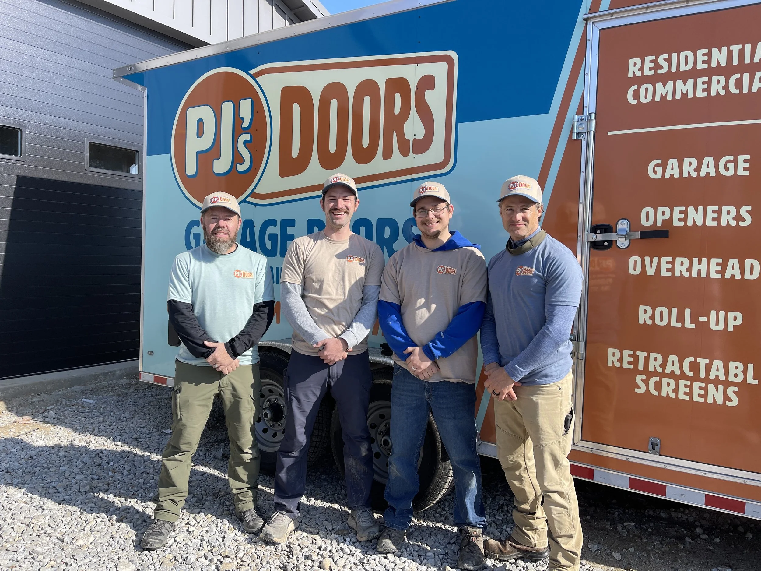 A man working on installing a white garage door in a garage construction site, with an open garage space and wooden framing inside.