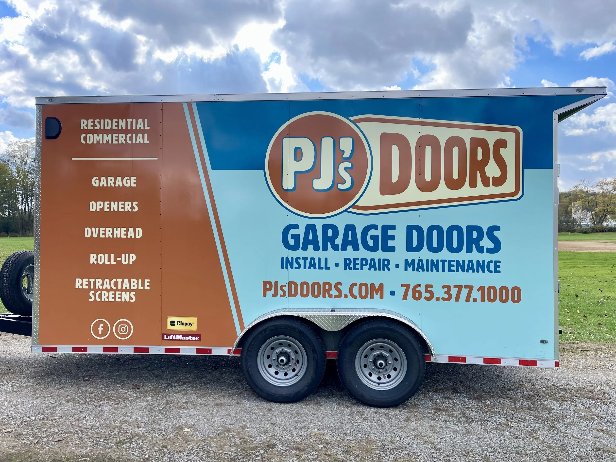 Two smiling men taking a selfie indoors, with a garage door in the background. One wears a black cap, and the other wears a gray cap with a 'New Horizons' logo.
