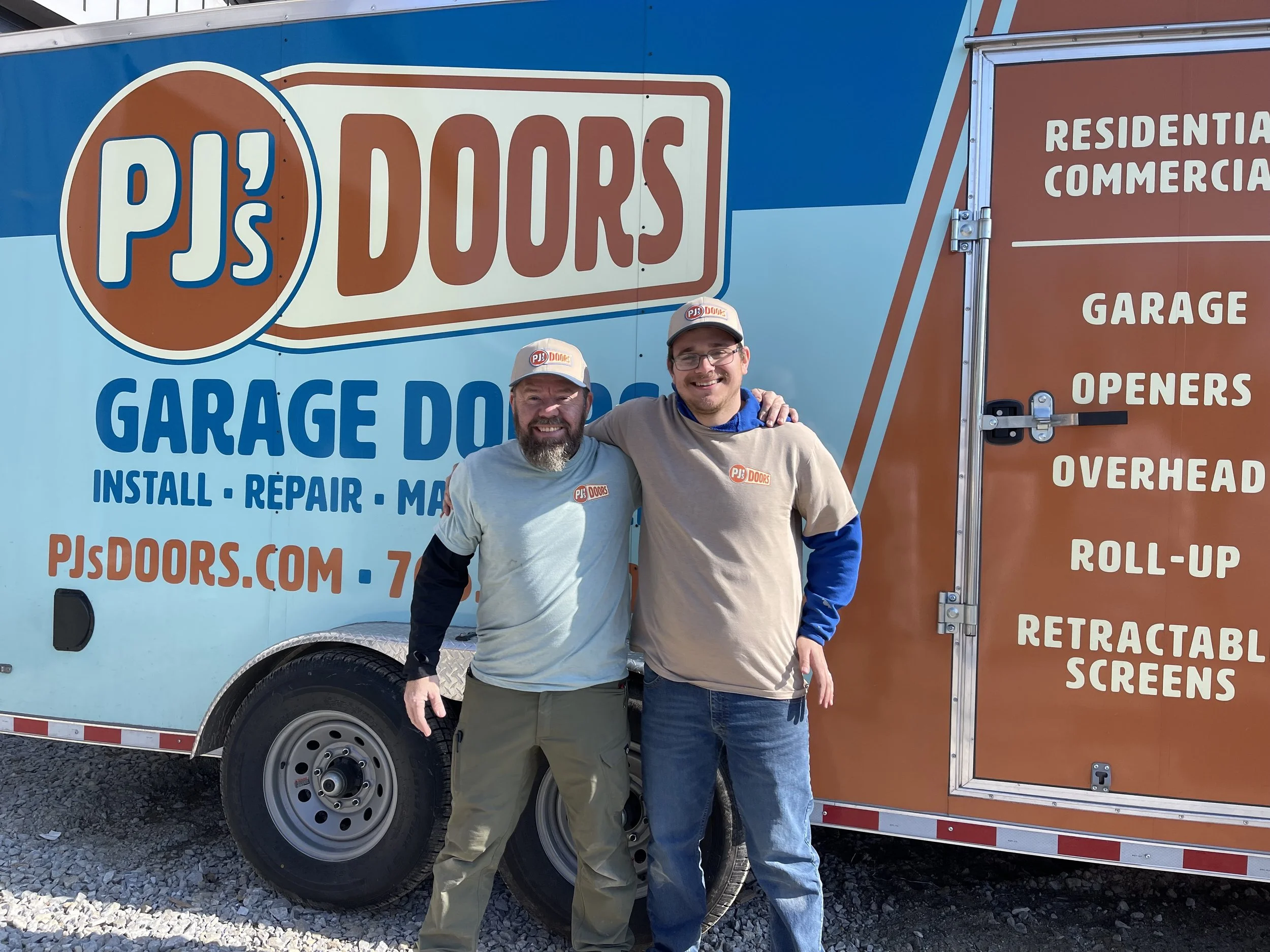 A man working on installing a white garage door in a garage construction site, with an open garage space and wooden framing inside.