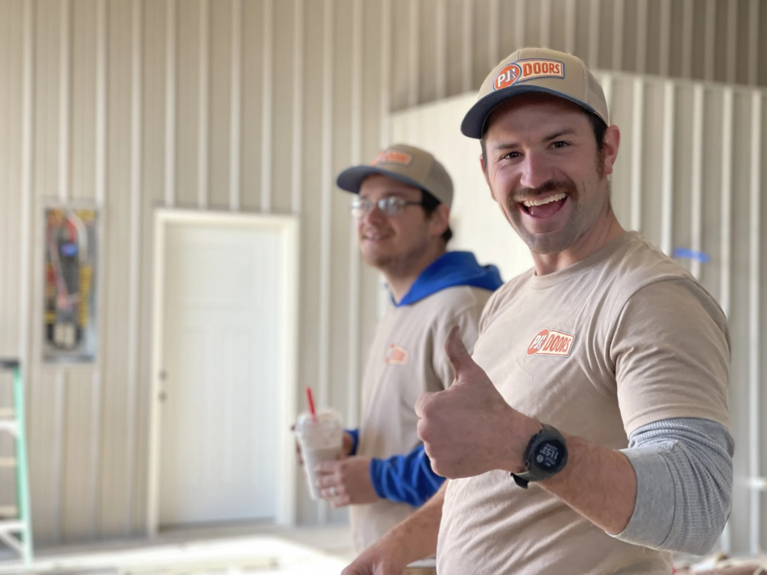 A man working on installing a white garage door in a garage construction site, with an open garage space and wooden framing inside.