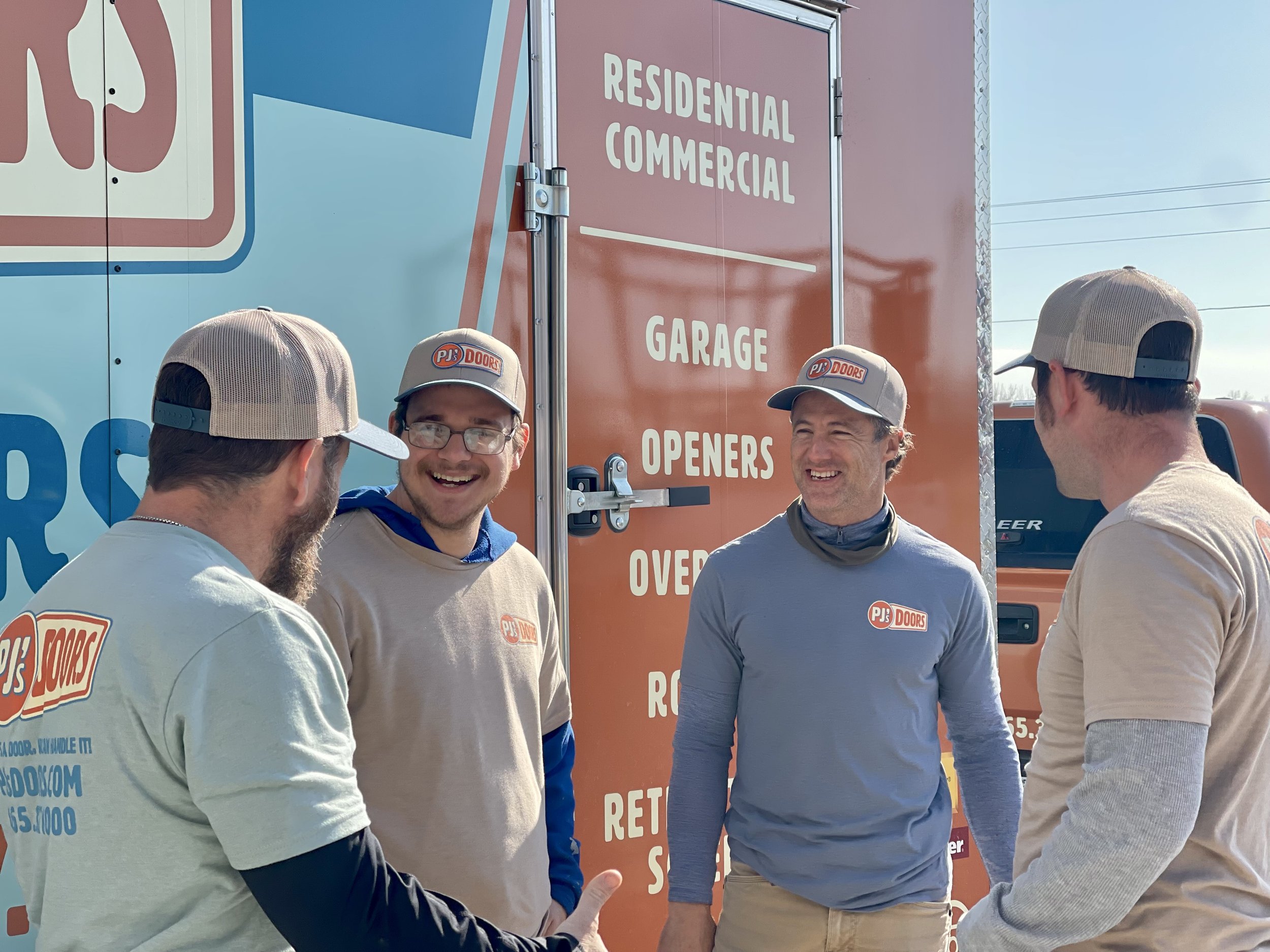 A man working on installing a white garage door in a garage construction site, with an open garage space and wooden framing inside.