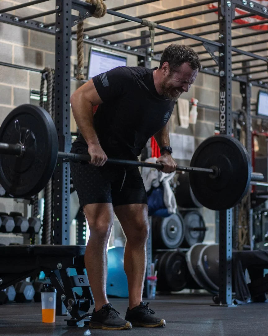 A man in a gym lifting a barbell with weights during a workout.