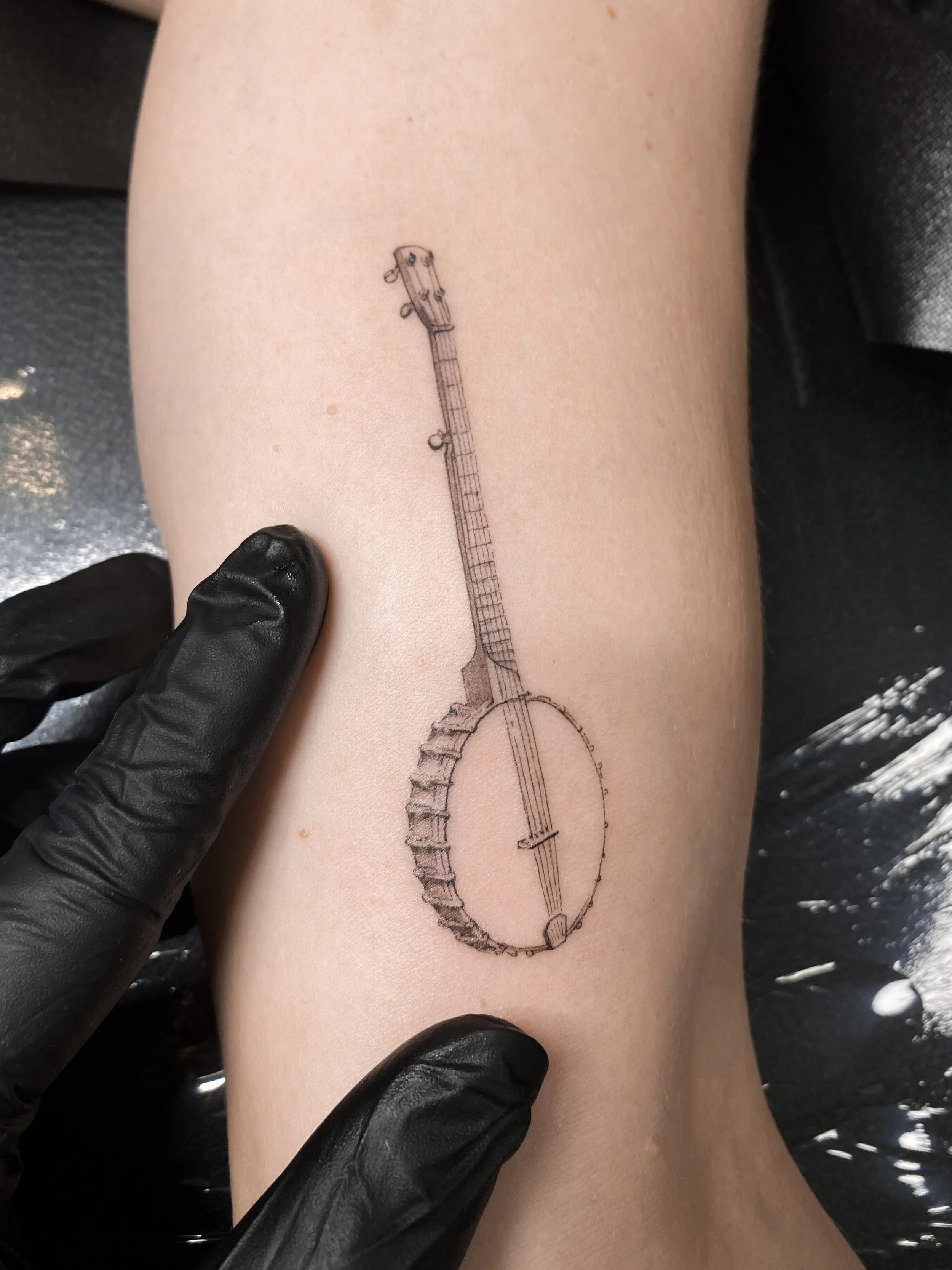 Tattoo of a banjo on a person's arm.