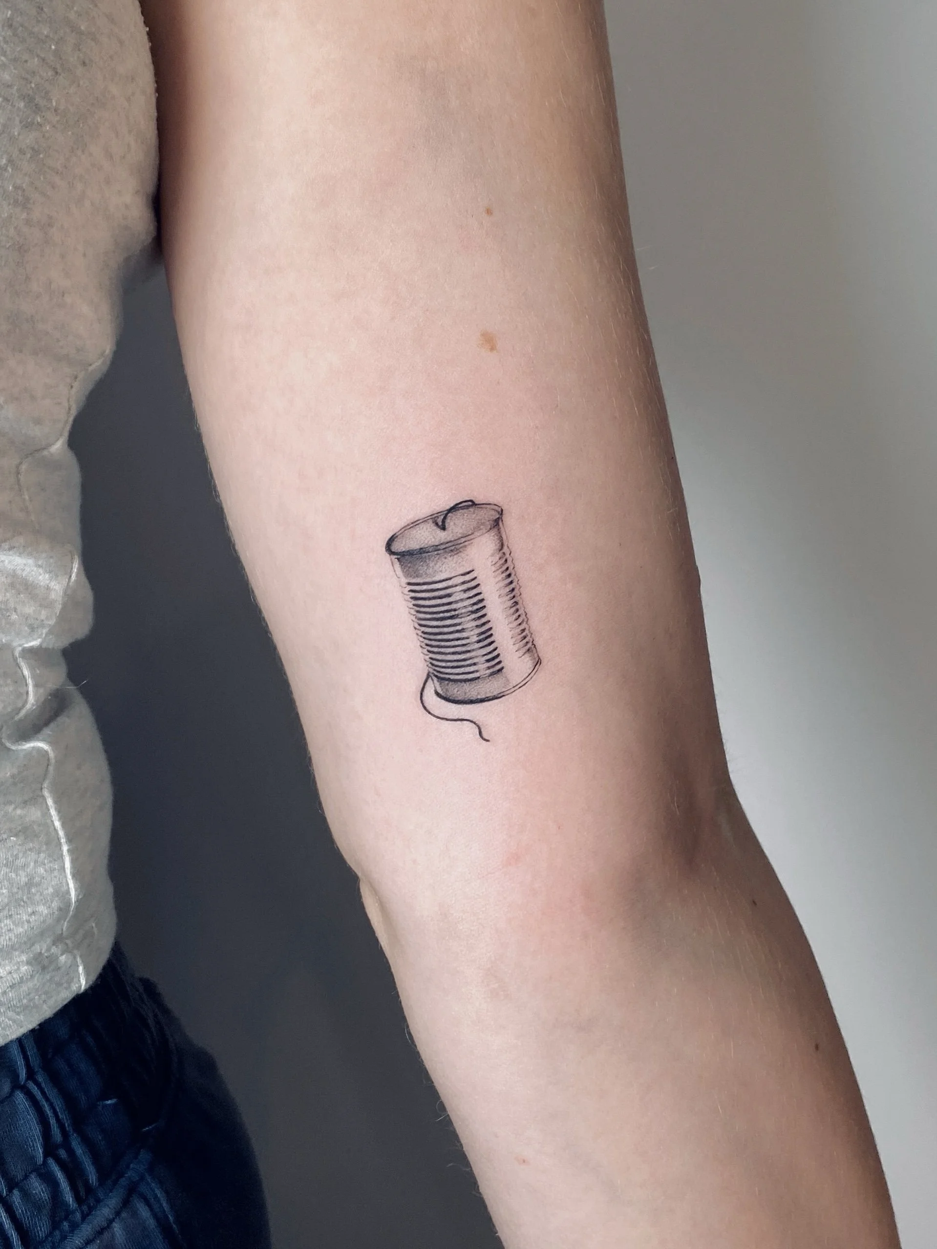Tattoo of a can of soup on a person's arm.
