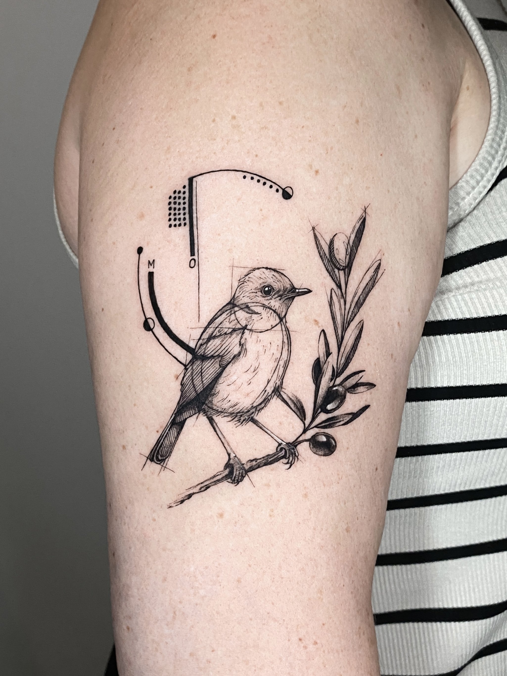 Tattoo of a bird perched on a branch with leaves and berries, surrounded by abstract geometric and scientific design elements.
