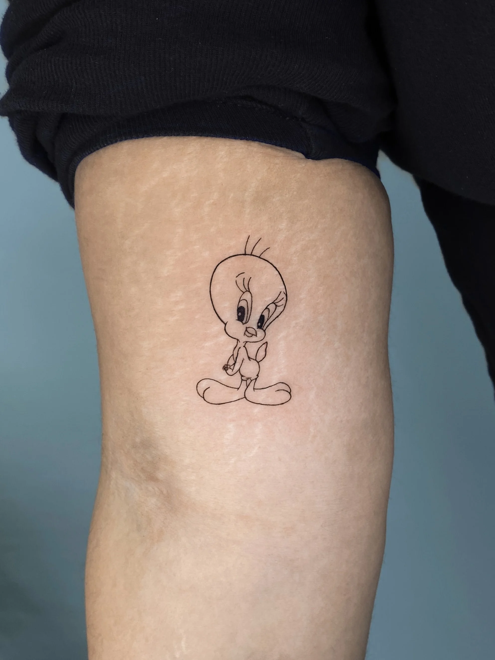 A tattoo of the cartoon character Tweety Bird on a person's thigh.