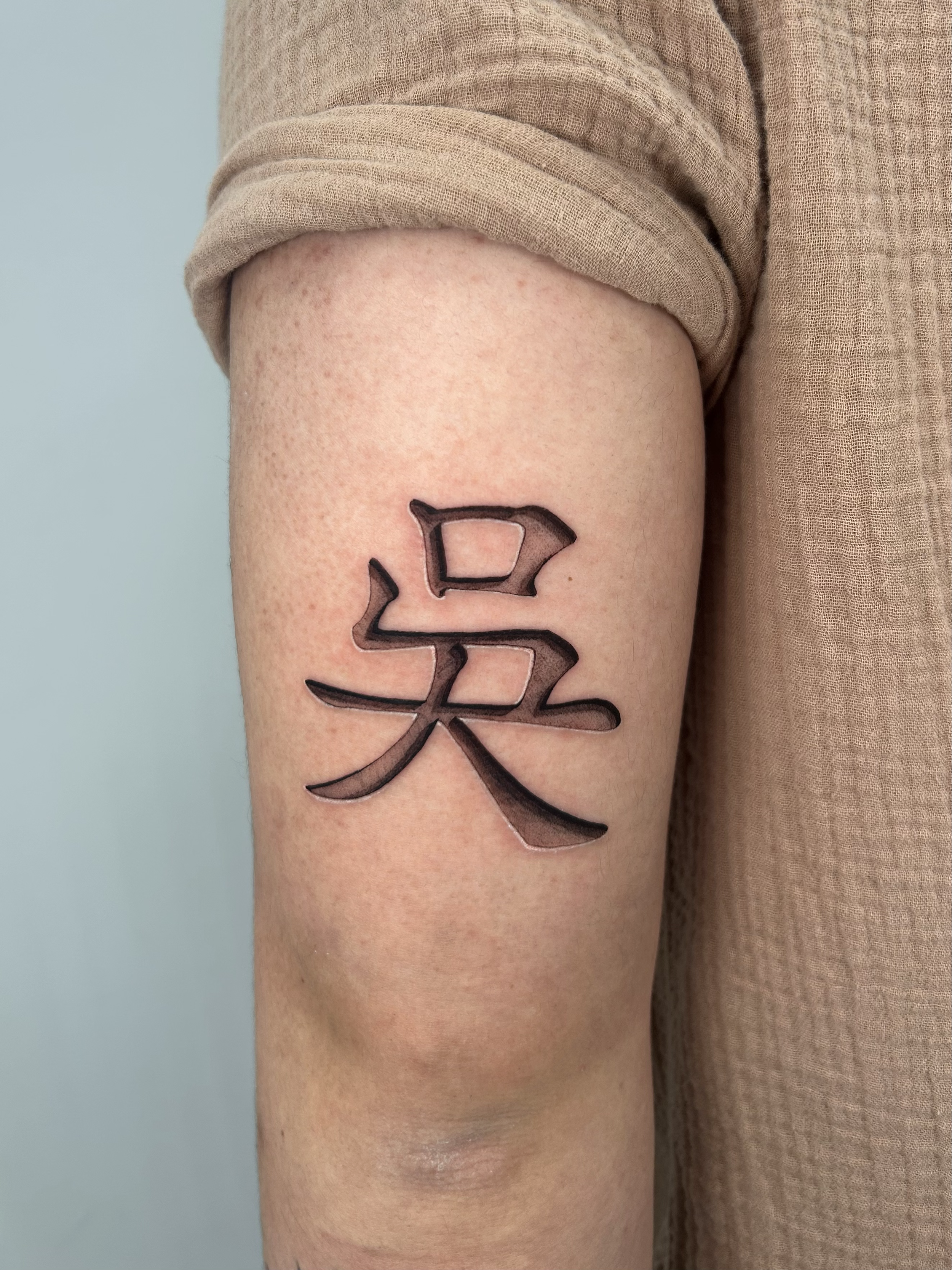 Tattoo of a Chinese character on a person's thigh, with rolled-up beige pants.