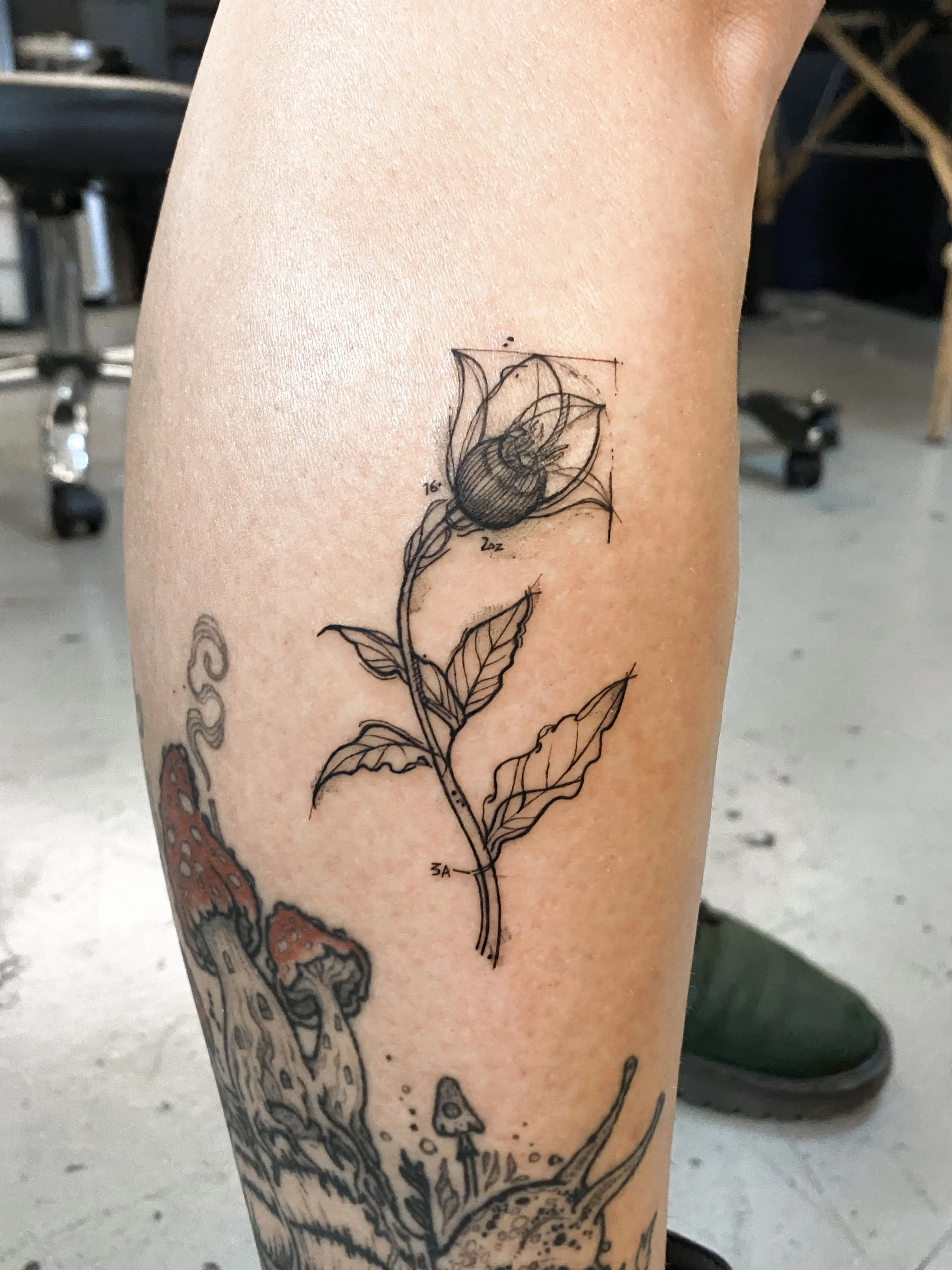 Line art tattoo of a flower with leaves, with detailed measurements and sketches.