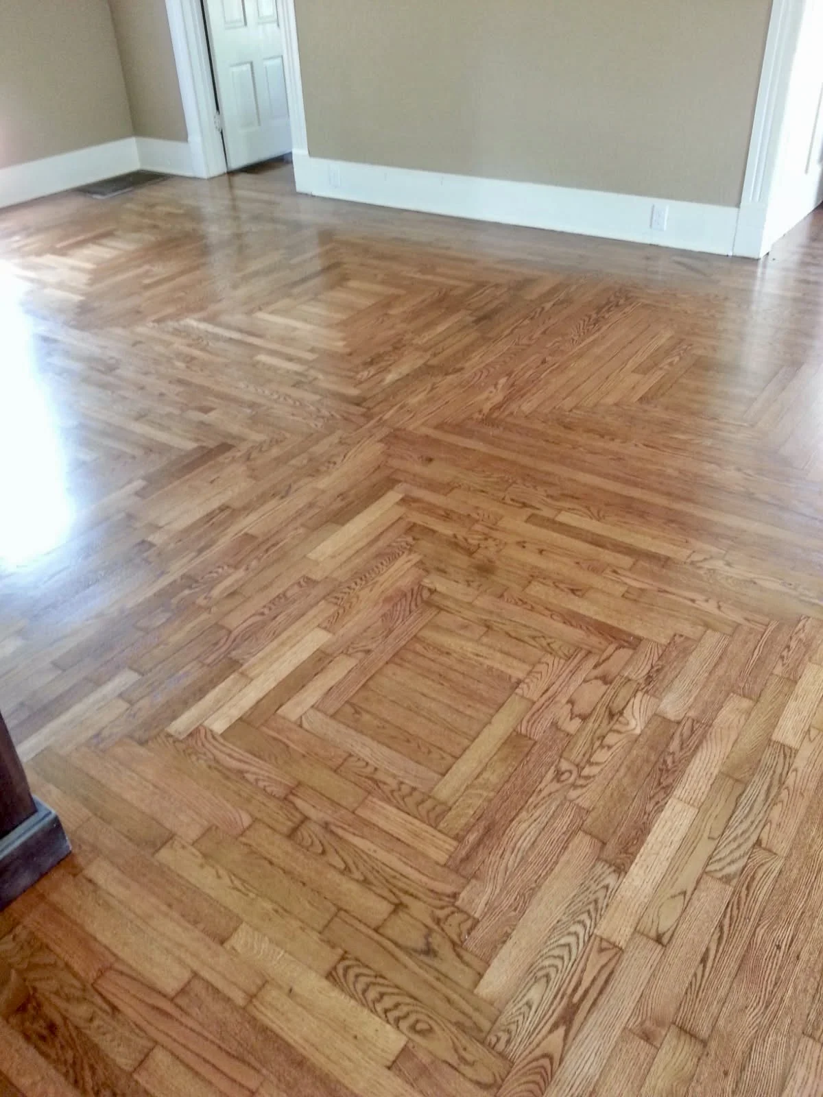 Wooden floor with a pattern of strips forming squares and rectangles in an empty room.