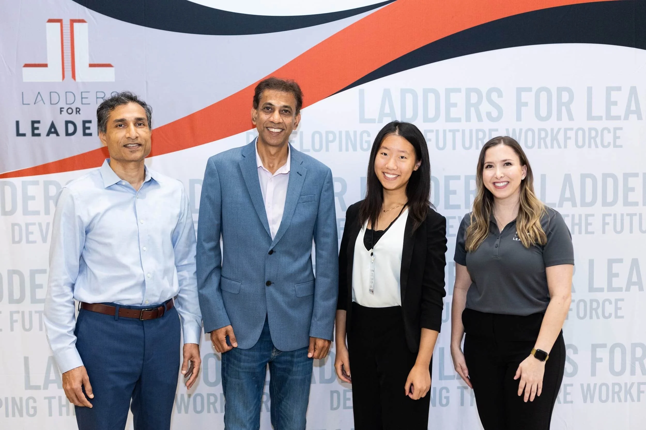 Four people standing in front of a backdrop with the text 'Ladders for Leaders' and a logo, smiling for the camera.