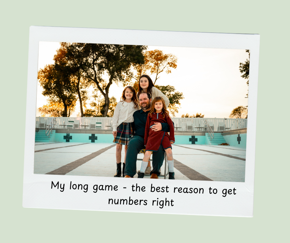 A man sitting on a chair with three young girls around him, at an empty outdoor pool at sunset.