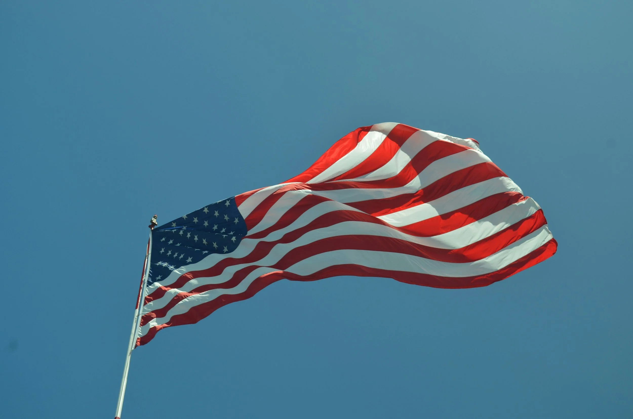 American flag flying against a clear blue sky.