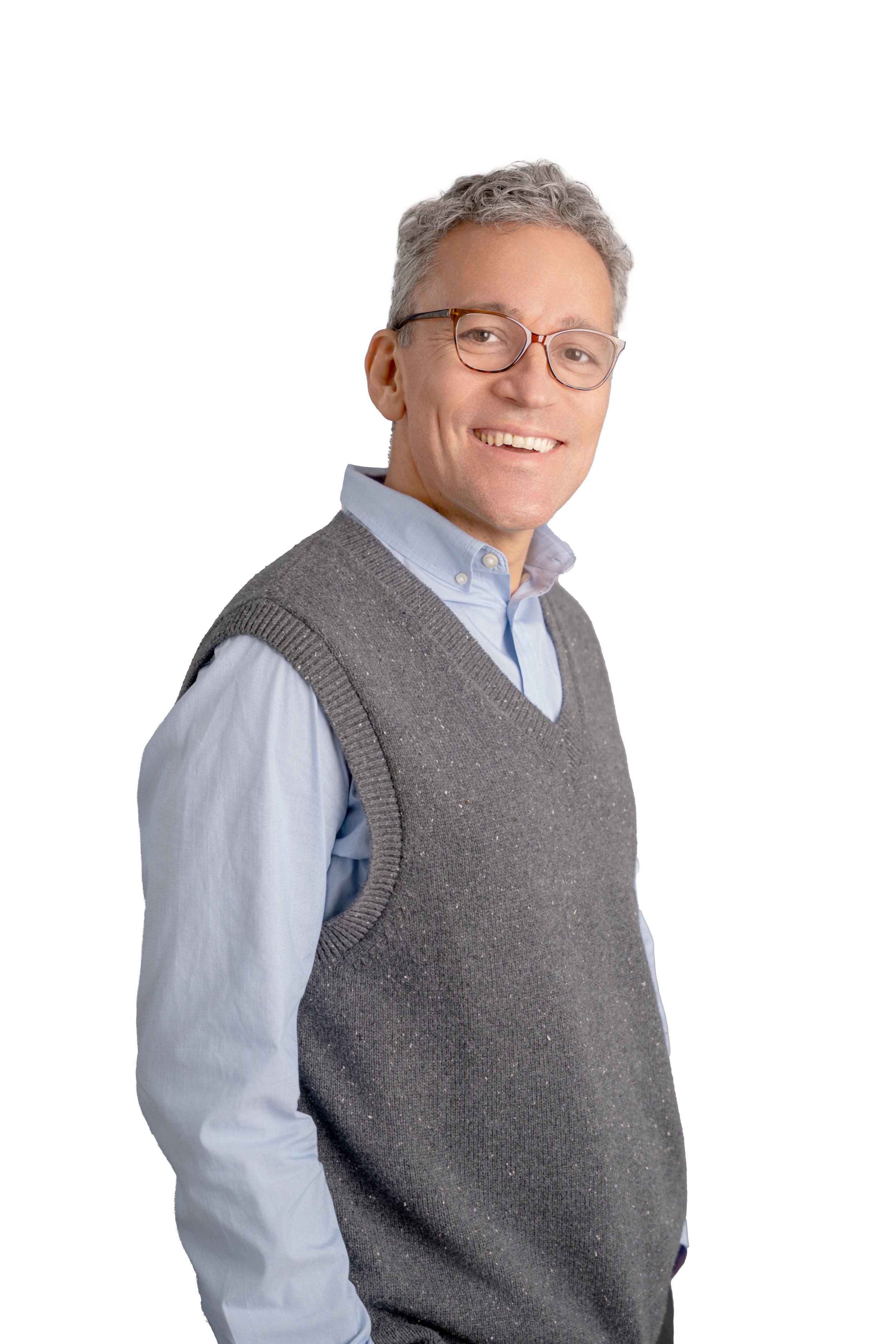 Smiling middle-aged man with glasses, wearing a light blue shirt and gray sweater vest, standing against a white background.