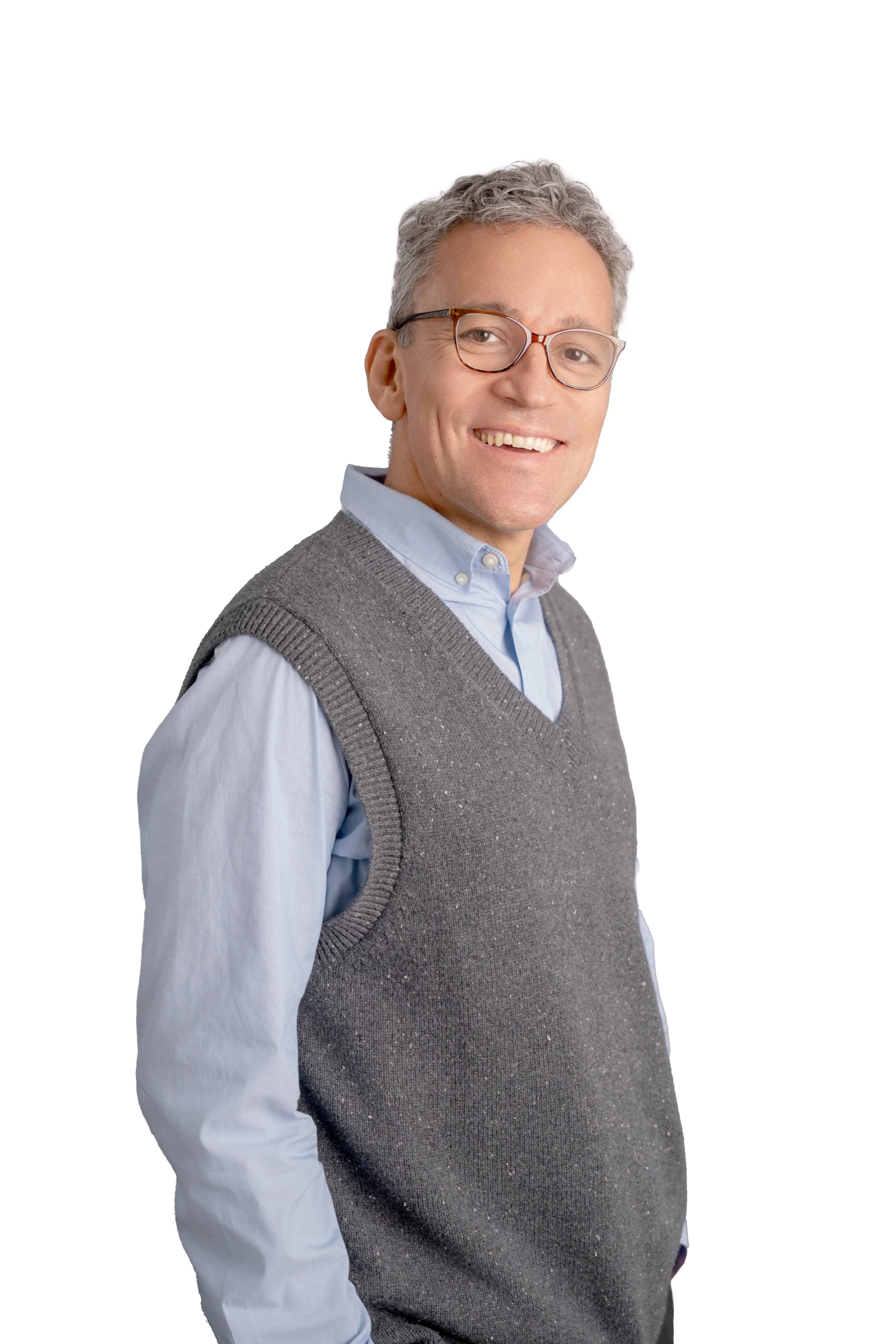 Smiling middle-aged man with gray hair and glasses, wearing a light blue collared shirt and a gray sweater vest, against a plain white background.