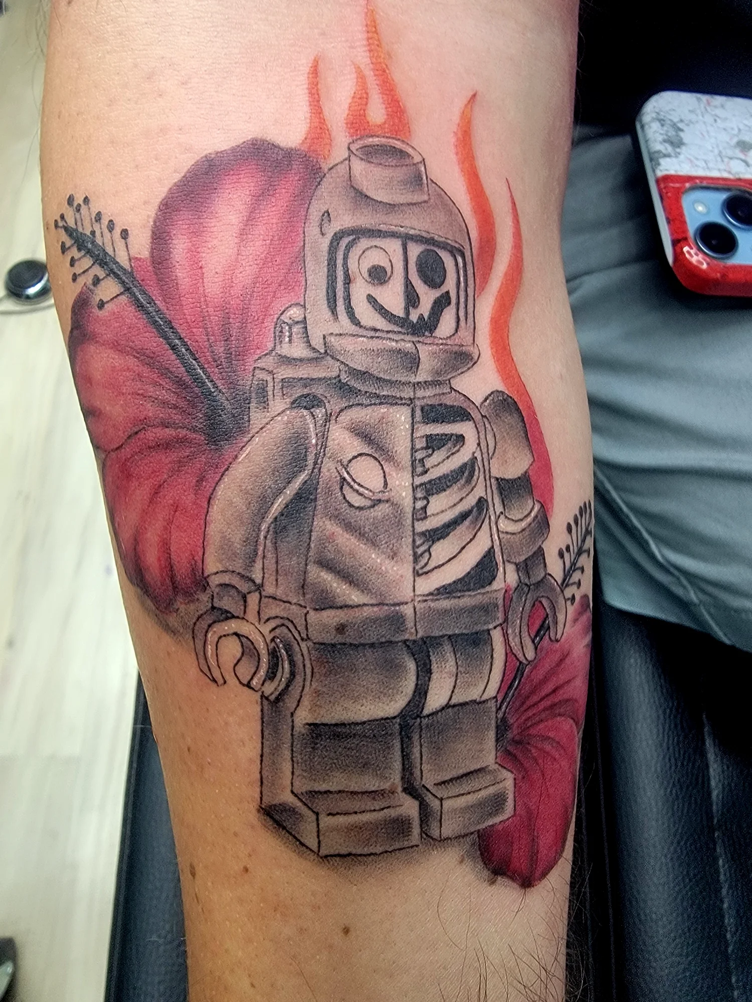 Tattoo of a rocket with a smiley face in front of a peach and red background.