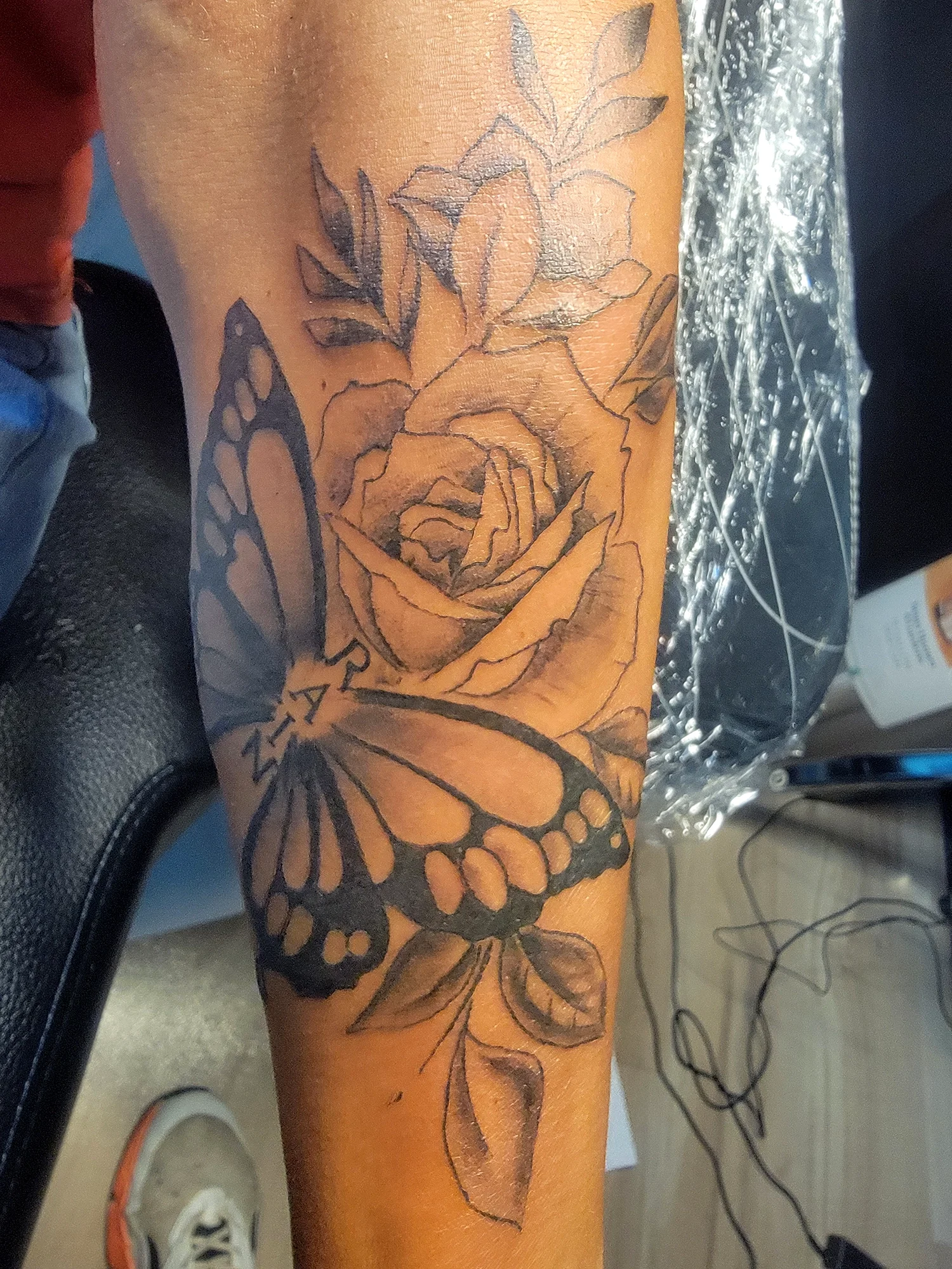 A tattoo of a rose and butterfly on a person's arm.